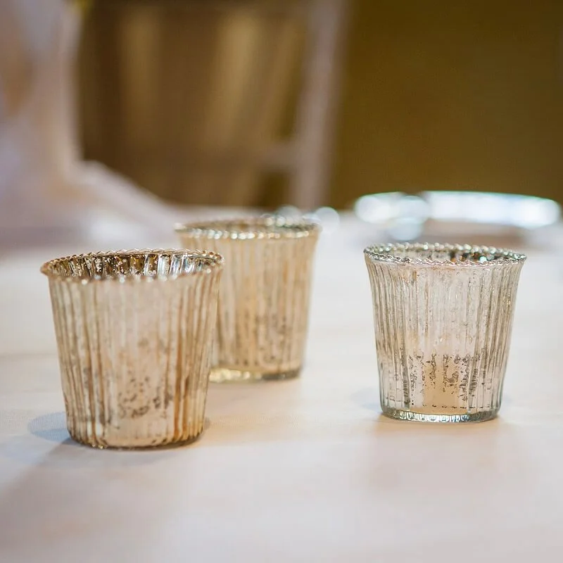 Gold Fluted Tealights with textured reflective gold finish, available to hire for your wedding or event, arranged on a white tablecloth.