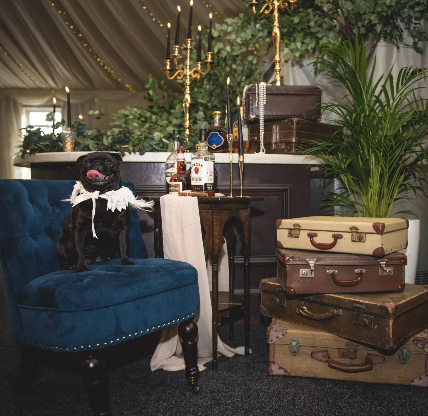 Dark Blue Feature Chair in velvet with studded trim, available to hire for your wedding or event, styled with vintage suitcases and candlelit table.