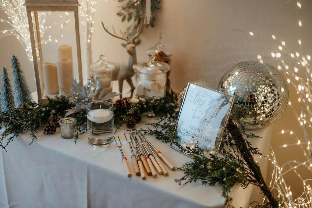 Smores Station with marshmallows, roasting forks, candles, and festive greenery, available to hire for your wedding or event.