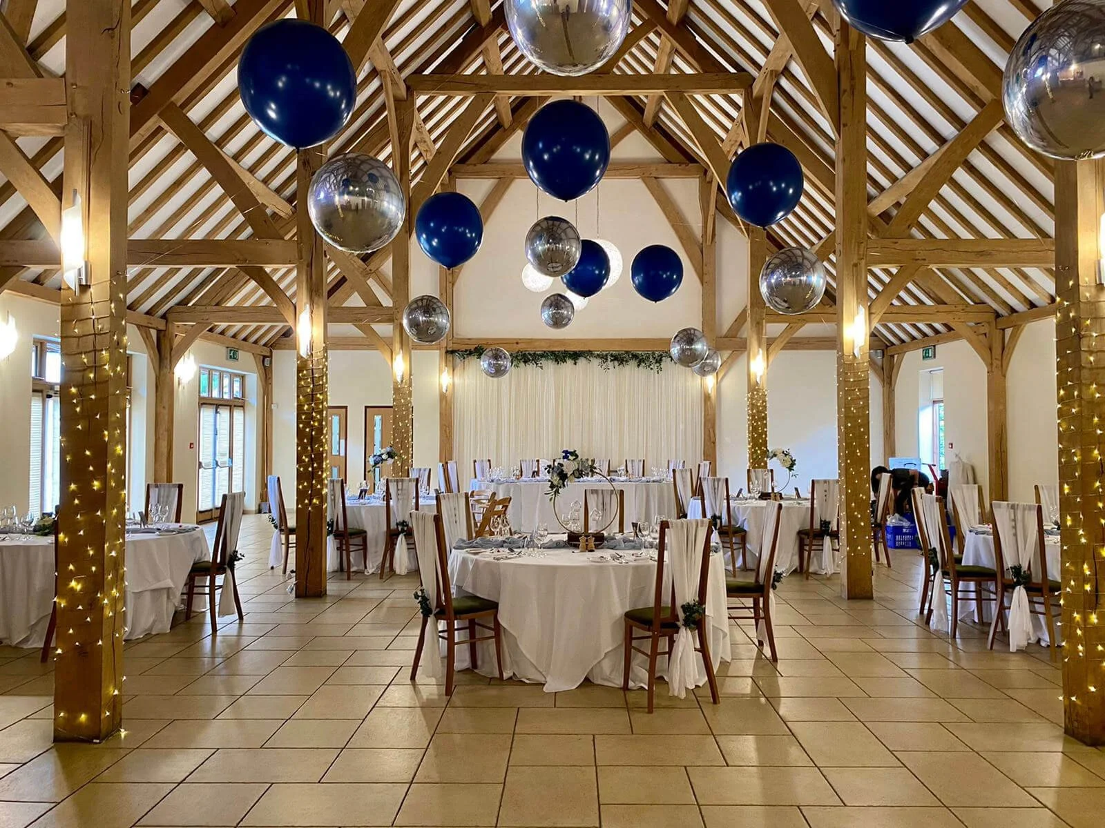 Floating Balloon Install Prices From with navy blue and silver balloons floating above decorated tables, available to hire for your wedding or event.