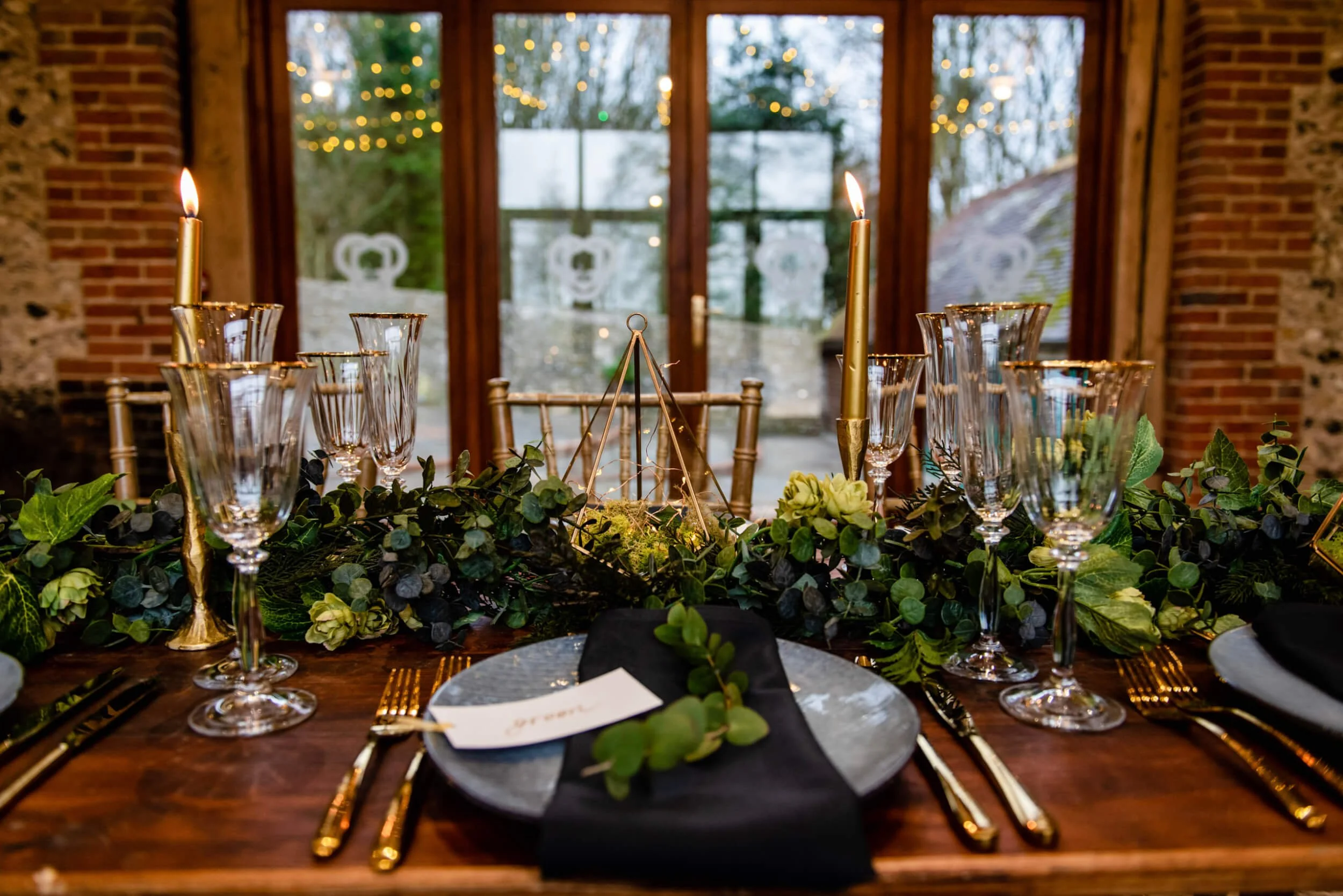 Faux Foliage decoration for tables Prices From styled as Faux Foliage decoration for tables with gold-rimmed glassware and lit gold candles, available to hire for your wedding or event.