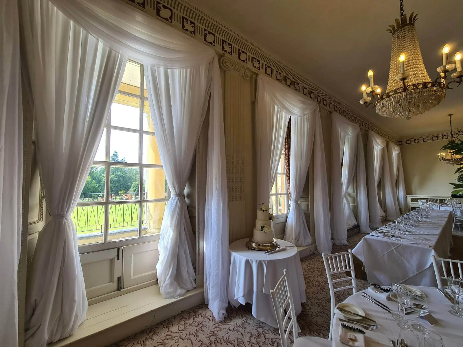Wall Draping Installation Prices From shown with white sheer curtains tied back in an elegant dining room, available to hire for your wedding or event.