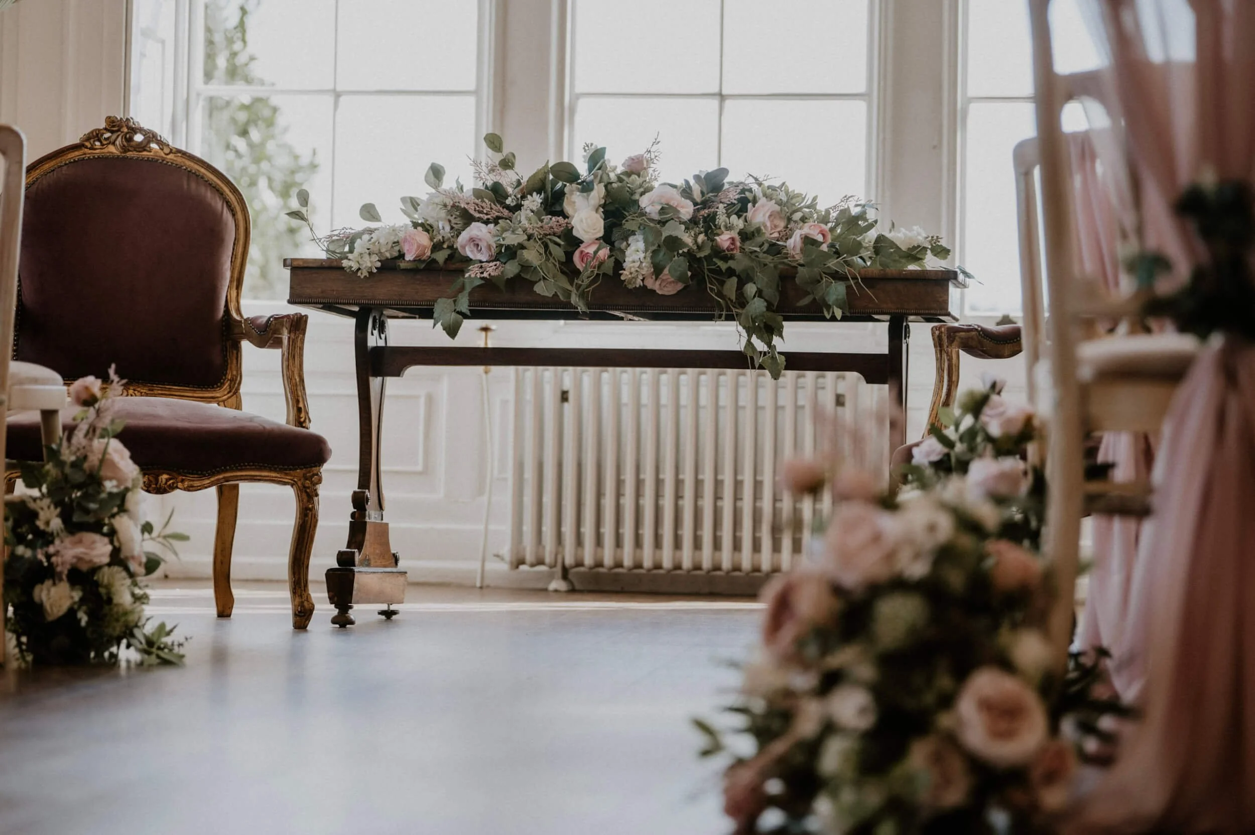 Faux Florals - Long & Low arrangement with pink and white flowers and greenery on wooden table, available to hire for your wedding or event.