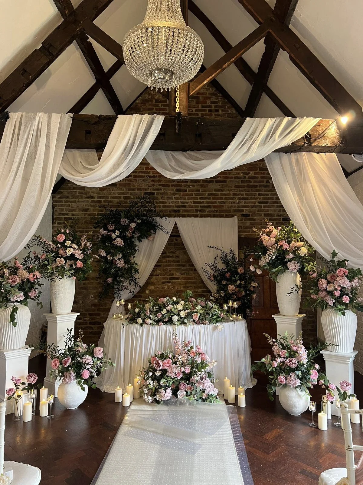 Ceremony/Bespoke Draping Prices To with white sheer draping and floral arrangements, available to hire for your wedding or event.