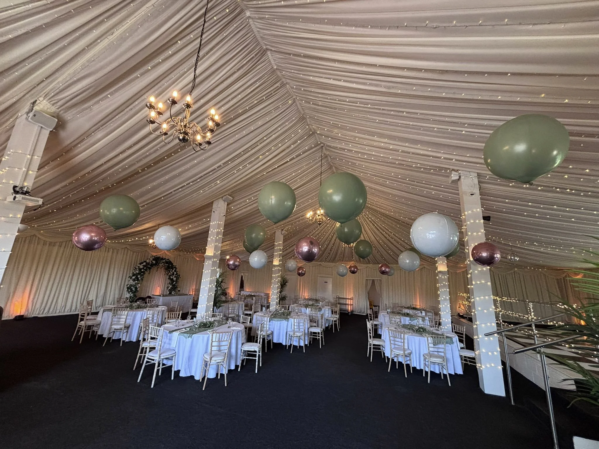 Floating Balloon Install Prices To with green, white, and pink balloons floating above tables in a decorated venue, available to hire for your wedding or event.
