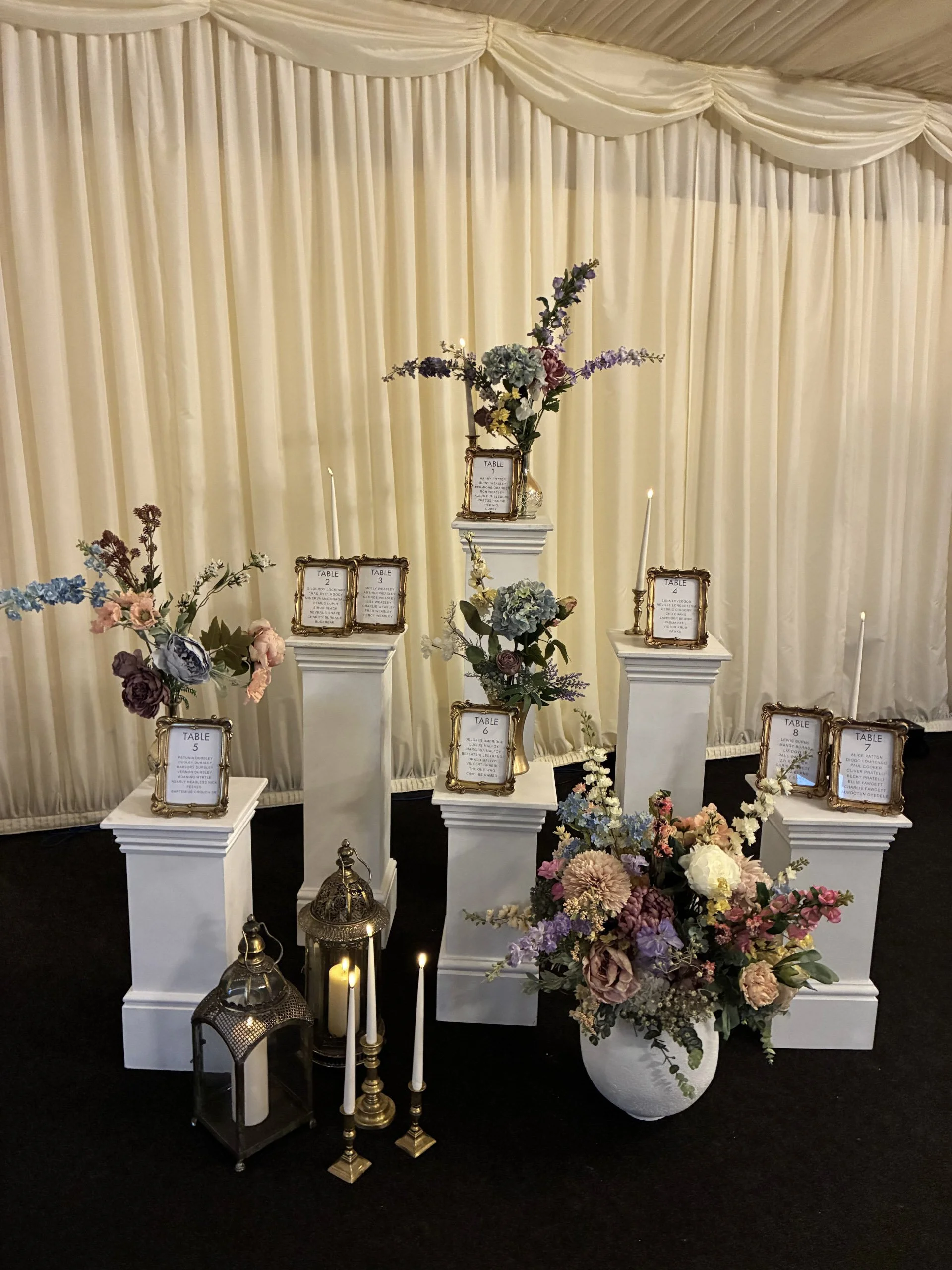White Plinth - Medium 30x30x60cm displayed with framed table numbers, pastel faux flowers, and candles, available to hire for your wedding or event.