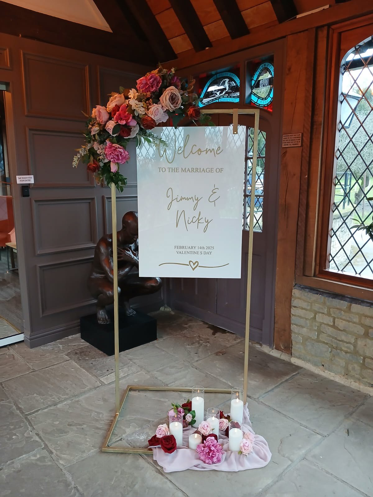 Gold hanging wedding welcome sign frame decorated with white flowers and greenery
