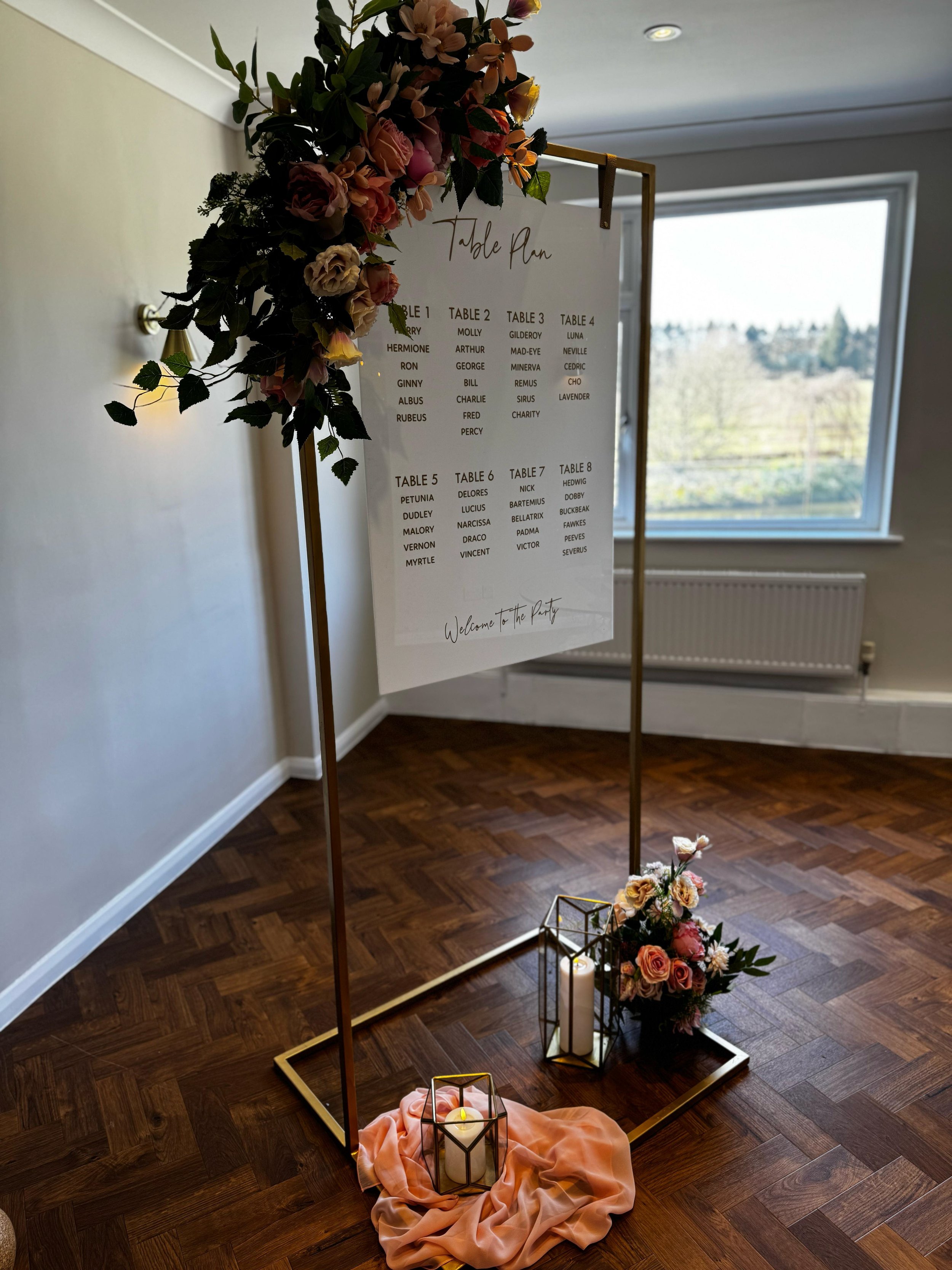 Gold hanging wedding welcome sign frame decorated with white flowers and greenery