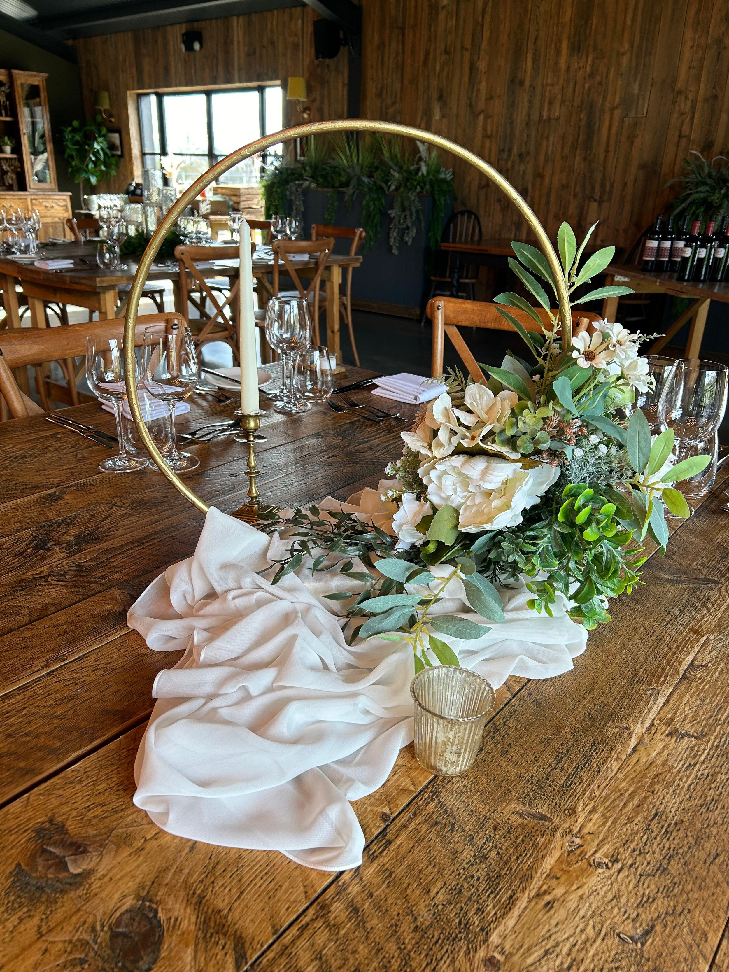Wedding hoop centrepiece styled with florals and greenery on a reception table