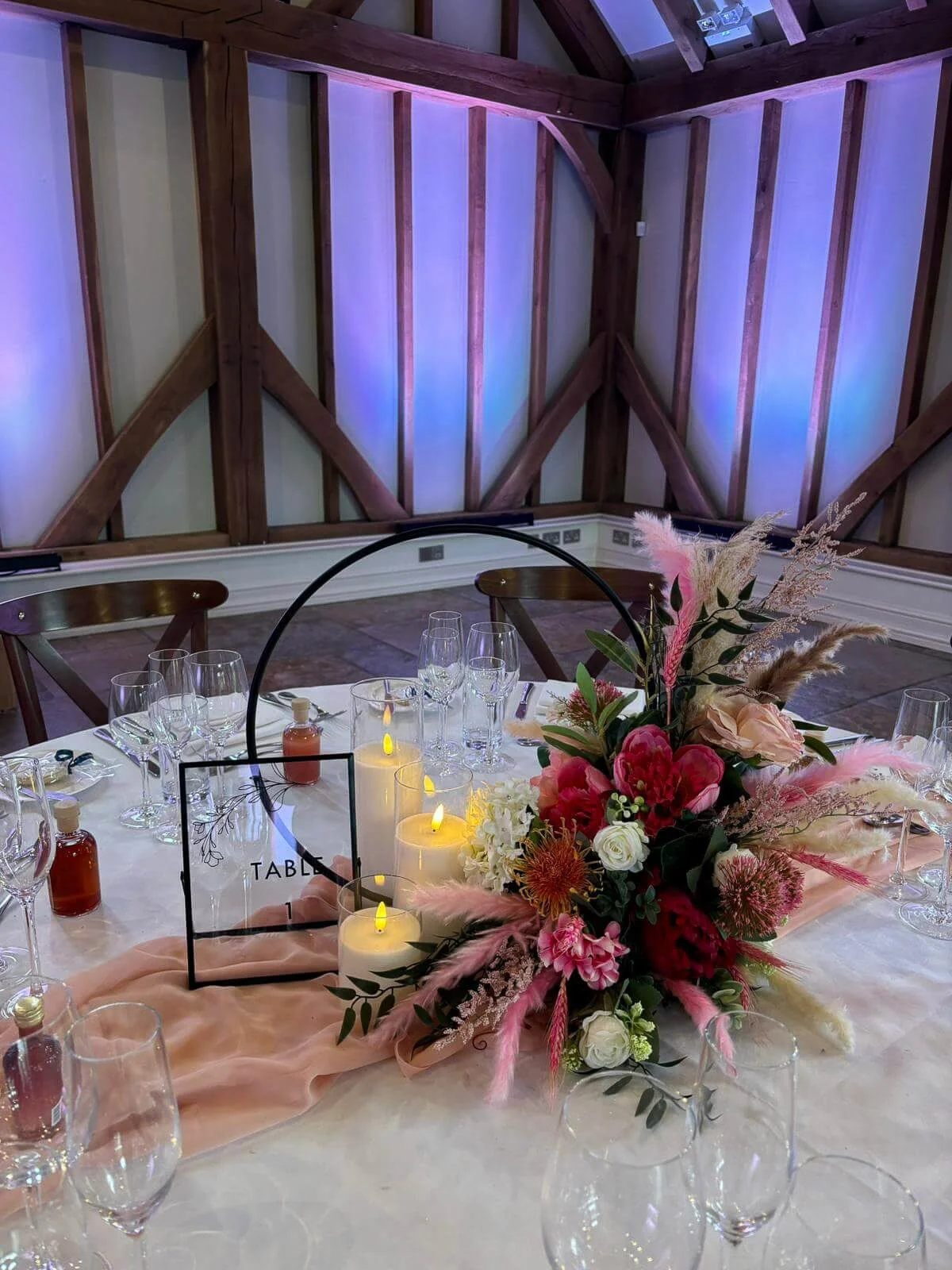 Wedding hoop centrepiece styled with florals and greenery on a reception table