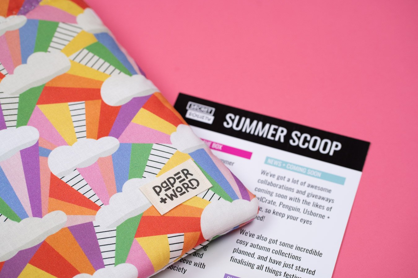 Paper and Word's Secret Society summer membership sleeve. This sleeve has white clouds with rainbow beams. It also shows the summer scoop, which is the membership newsletter