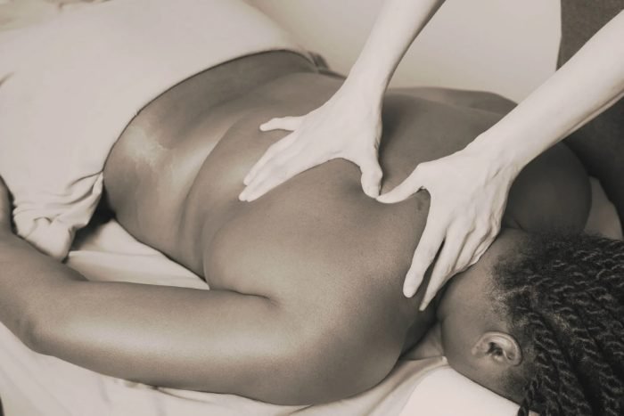 woman laying face down, receiving massage on shoulder