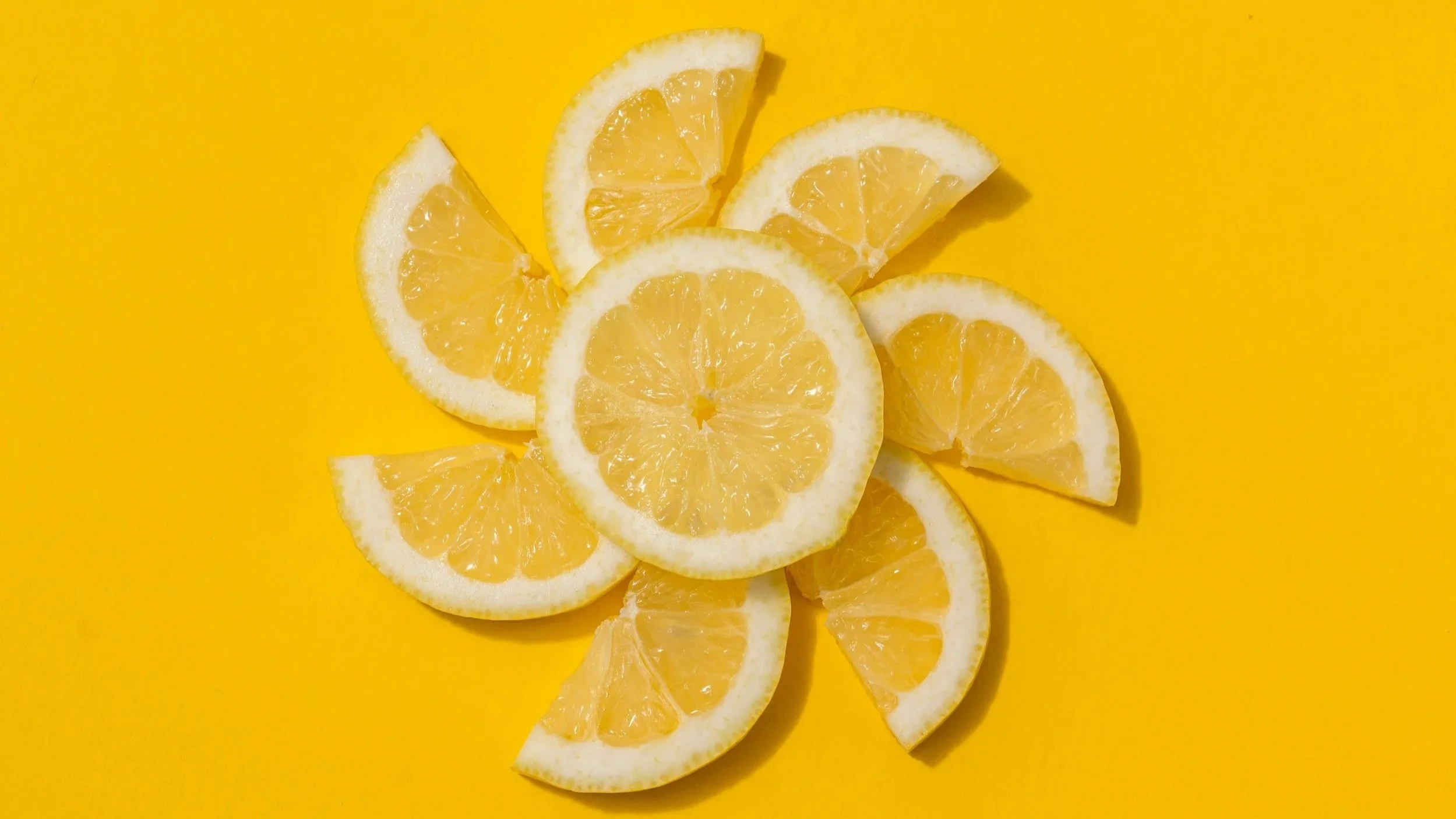 Lemon slices in the shape of a sun on a yellow background to explain essential oils safety and sun exposure.
