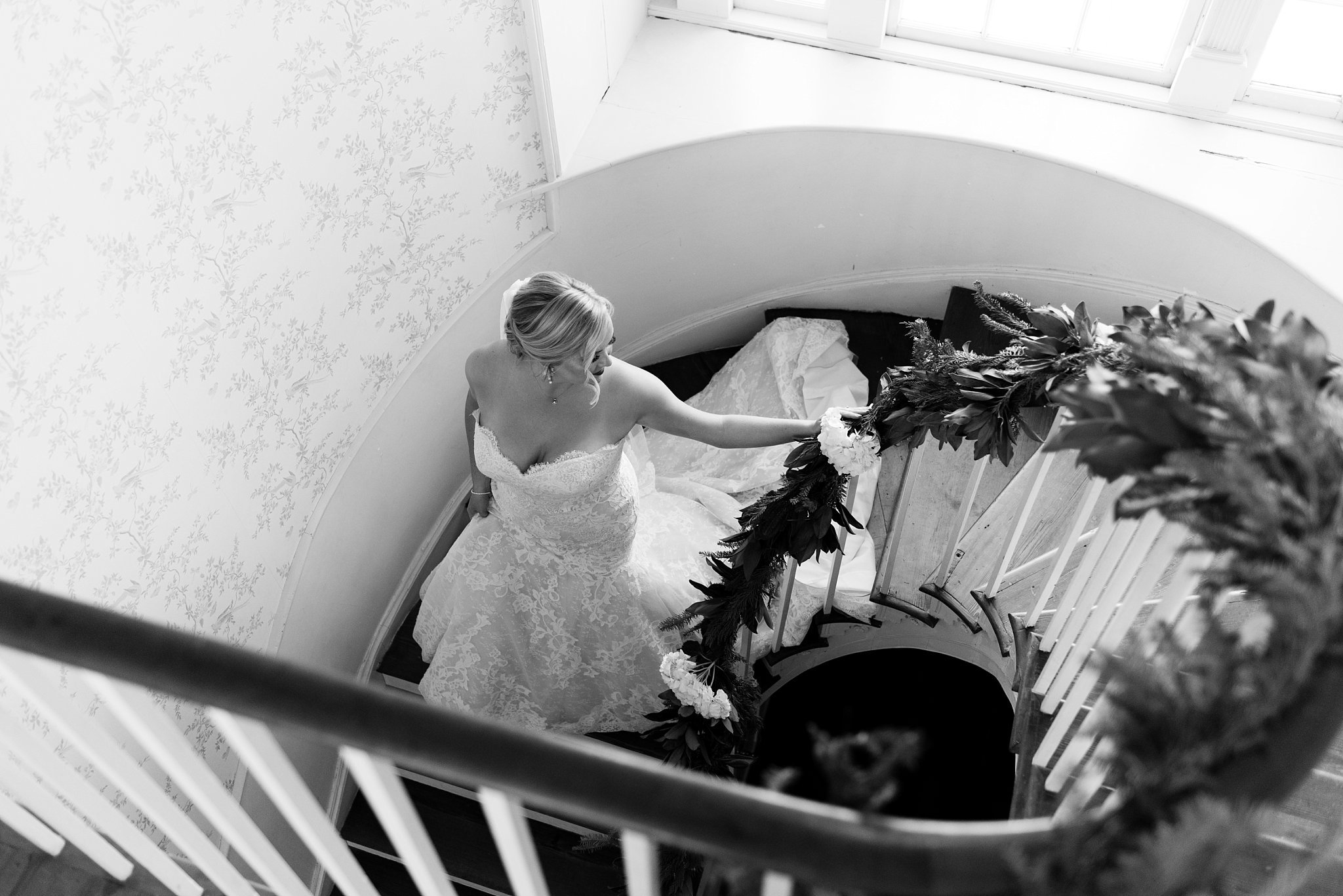 Spiral staircase in historic lowcountry wedding venue on the water. Southern bride walks down grand staircase photo taken by best light and airy fine art film Beaufort wedding photographer.