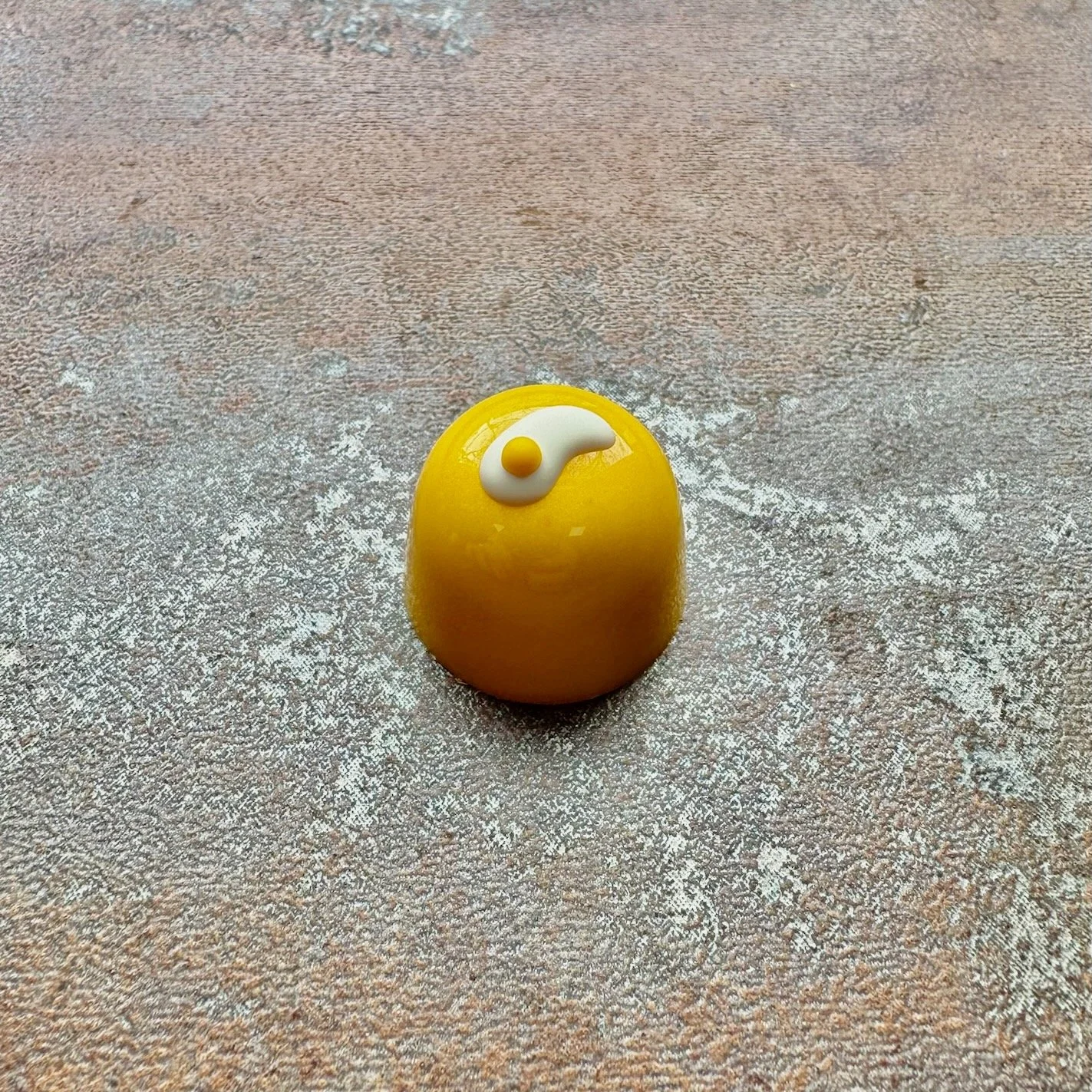 A yellow bonbon with 2 eyes that look like fried eggs