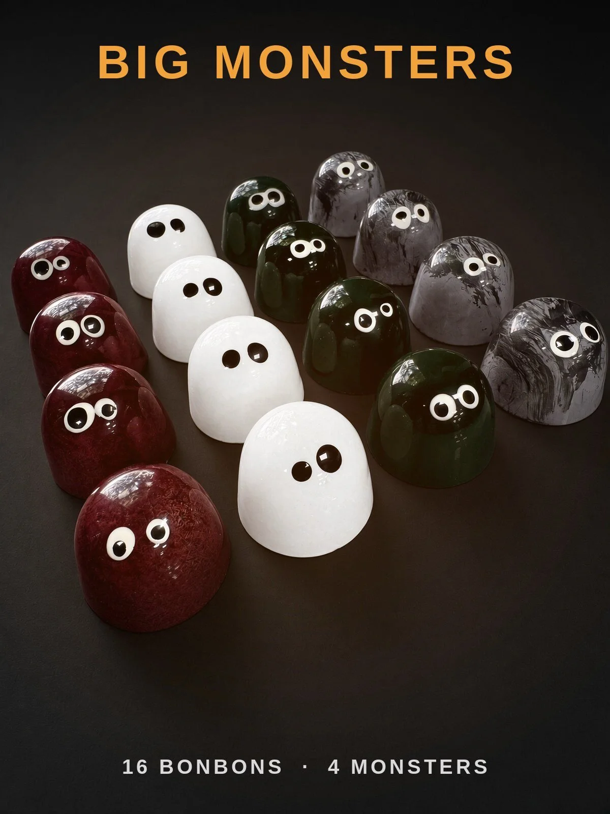 Big Monsters: sixteen Halloween bonbons with candy eyes in four rows of deep red Dracula, white Ghost, green Frankie and gray Wolfie, on a dark background.