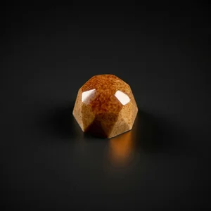 A glossy faceted tan chocolate bonbon with subtle speckling, sharply i