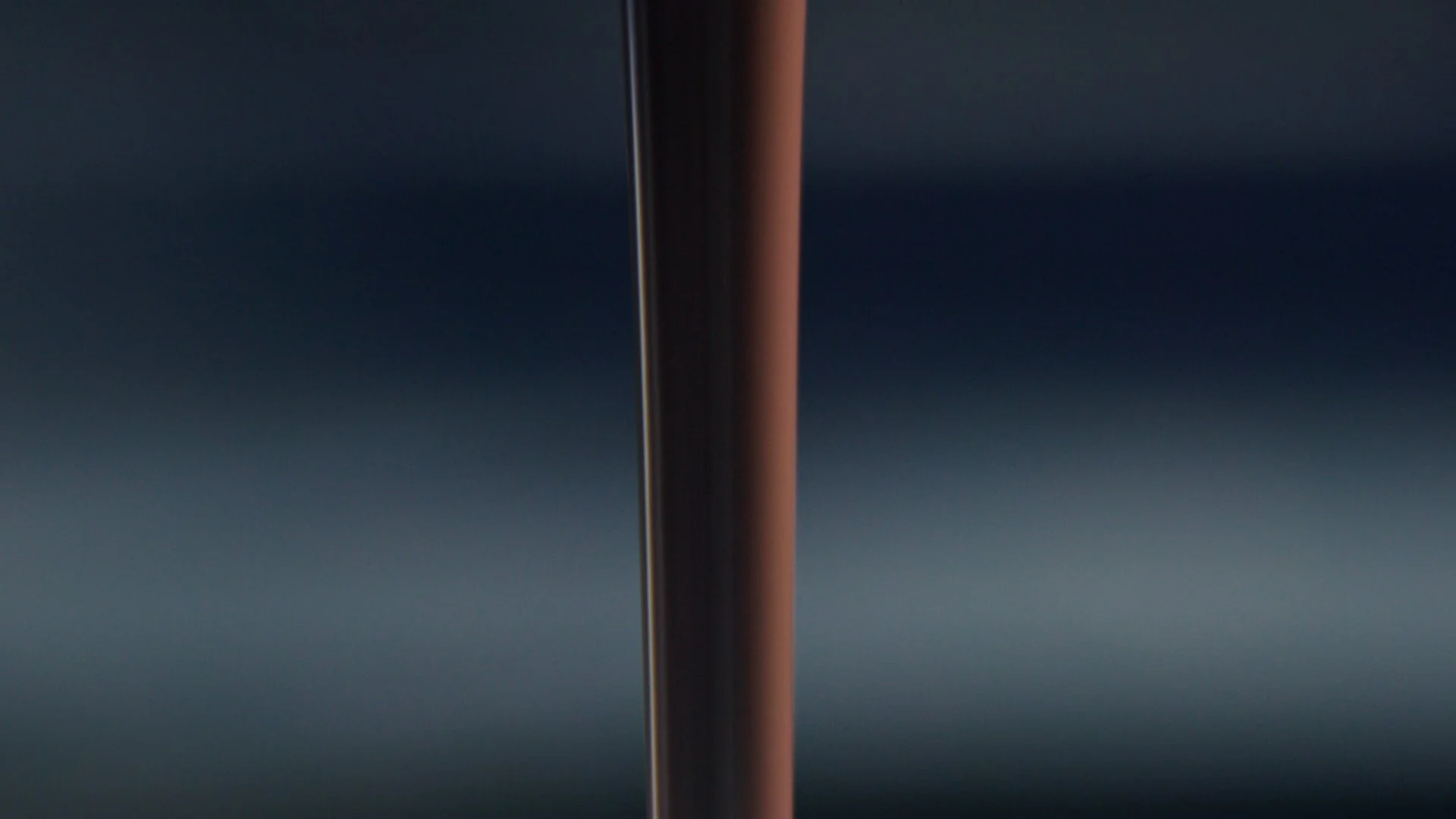 Close-up of a stream of chocolate flowing, against a dark background.