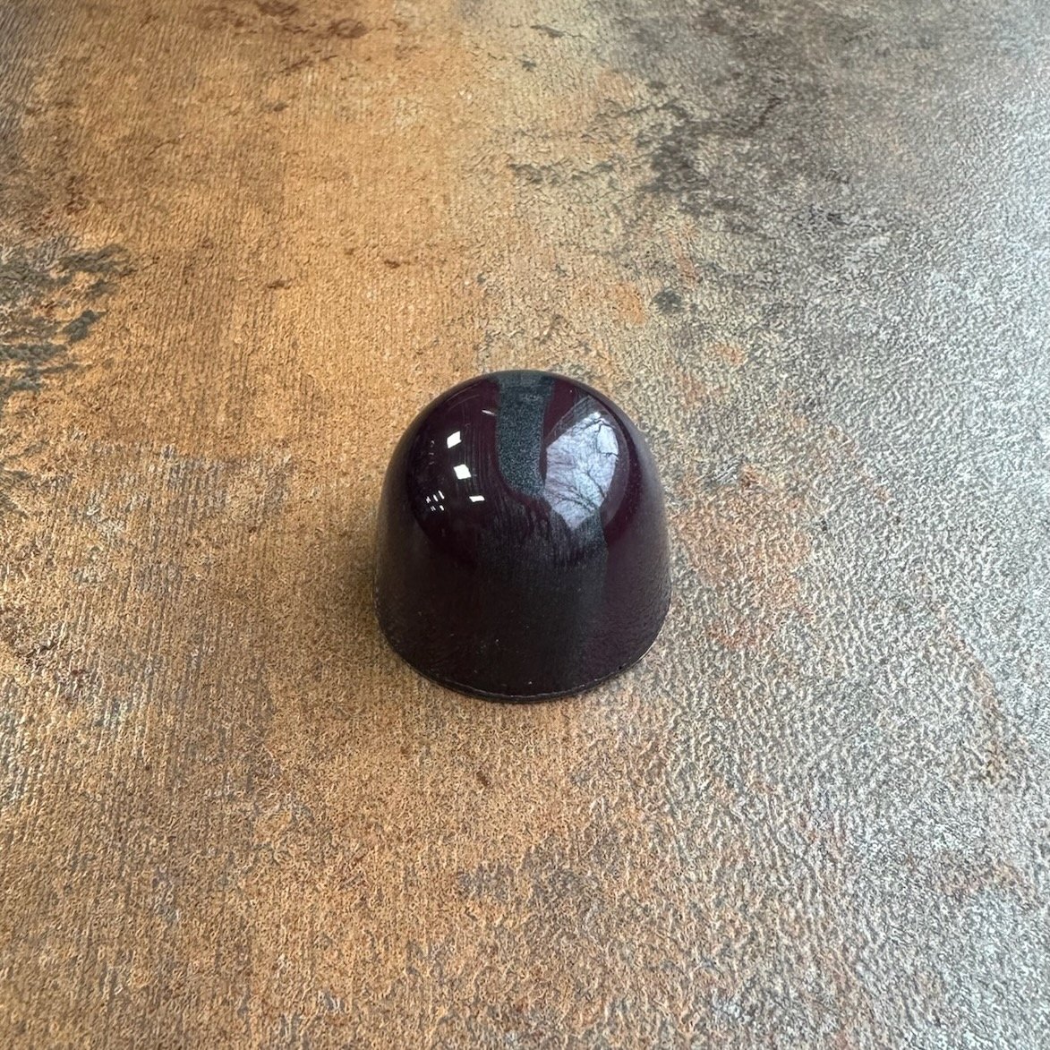 A Blackish domed chocolate bonbons with a blue streak