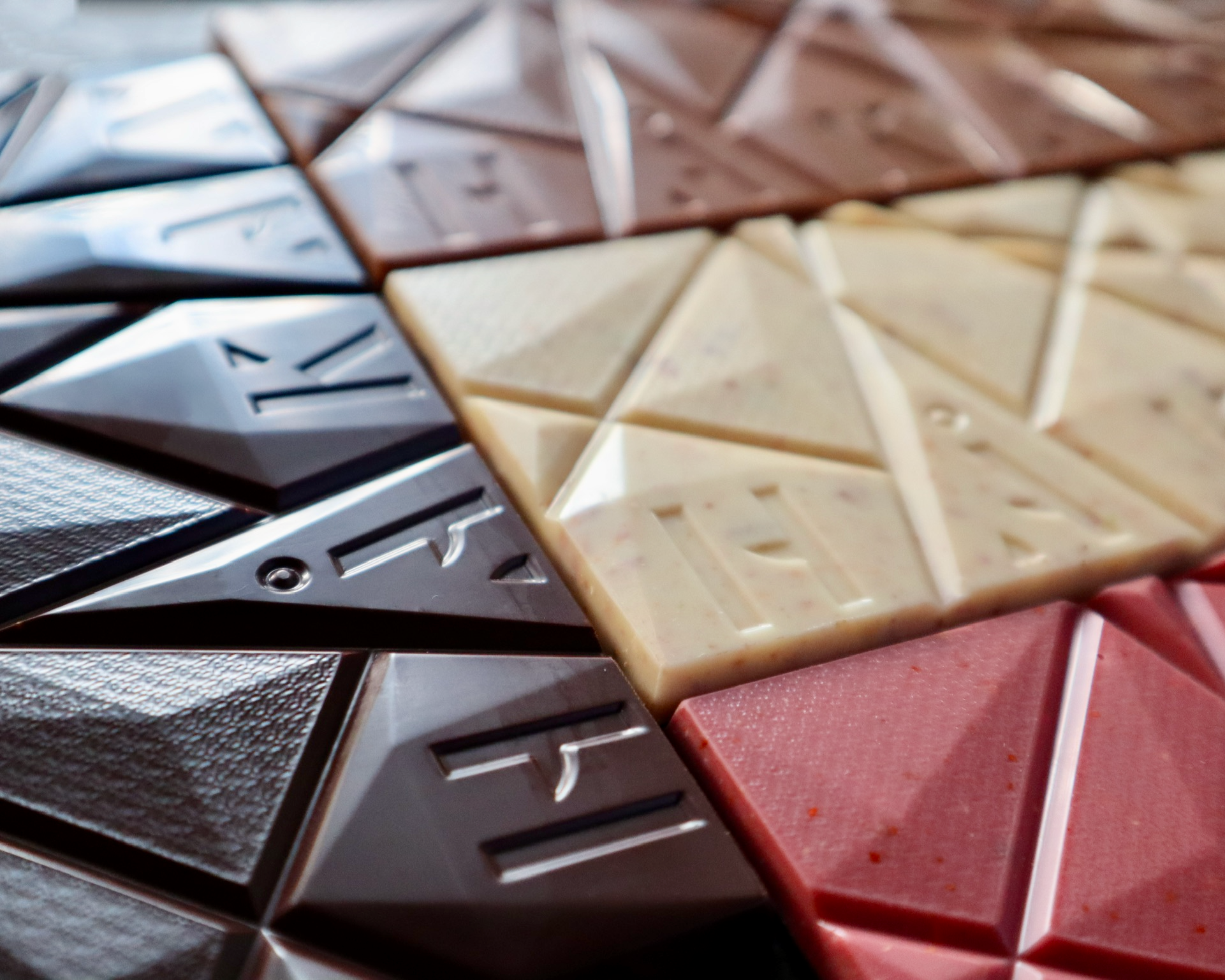 Close-up of 4 bars of chocolate in different colors and textures, arranged together.