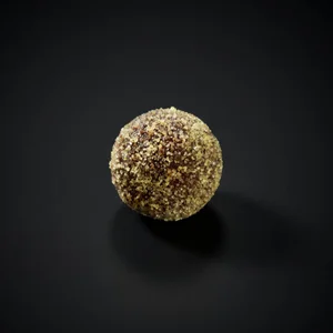 A passionfruit-coated chocolate bonbon covered in golden sugar crystal