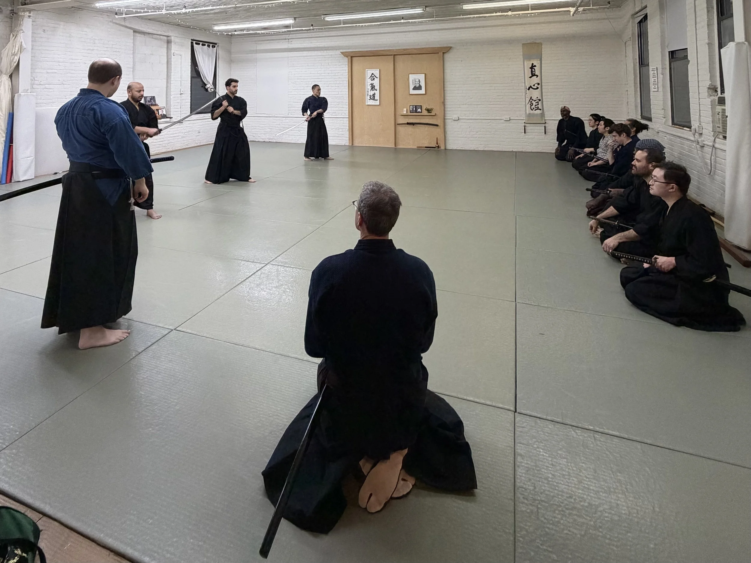 Students practice Japanese swordsmanship in a traditional dojo
