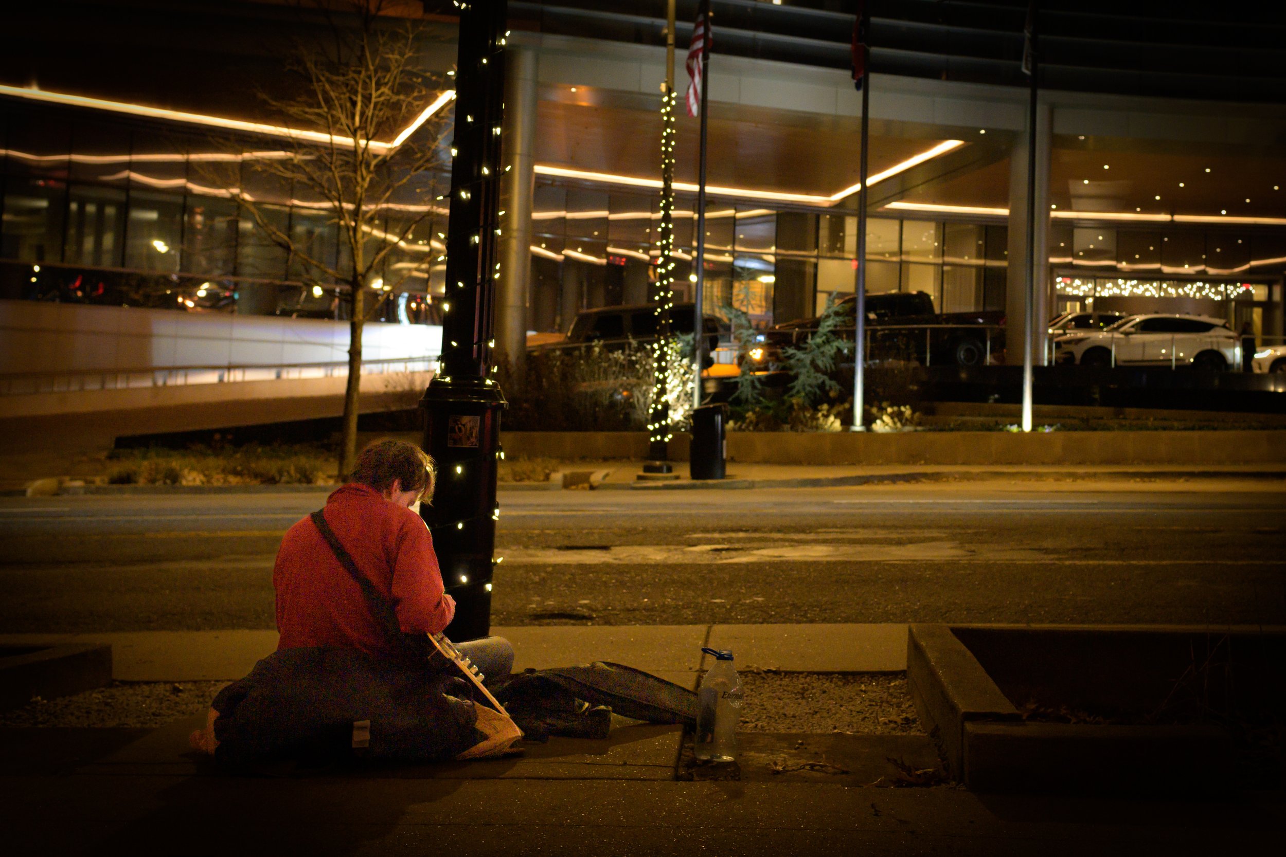  A young homeless man sits along the sidewalk of Eighth Avenue that parallels the Music City Convention Center . 