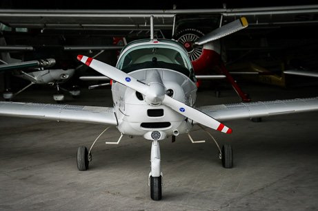 Front view of a small white propeller airplane parked inside a hangar, highlighting safety compliance and aviation fire extinguisher inspection services in Denver.