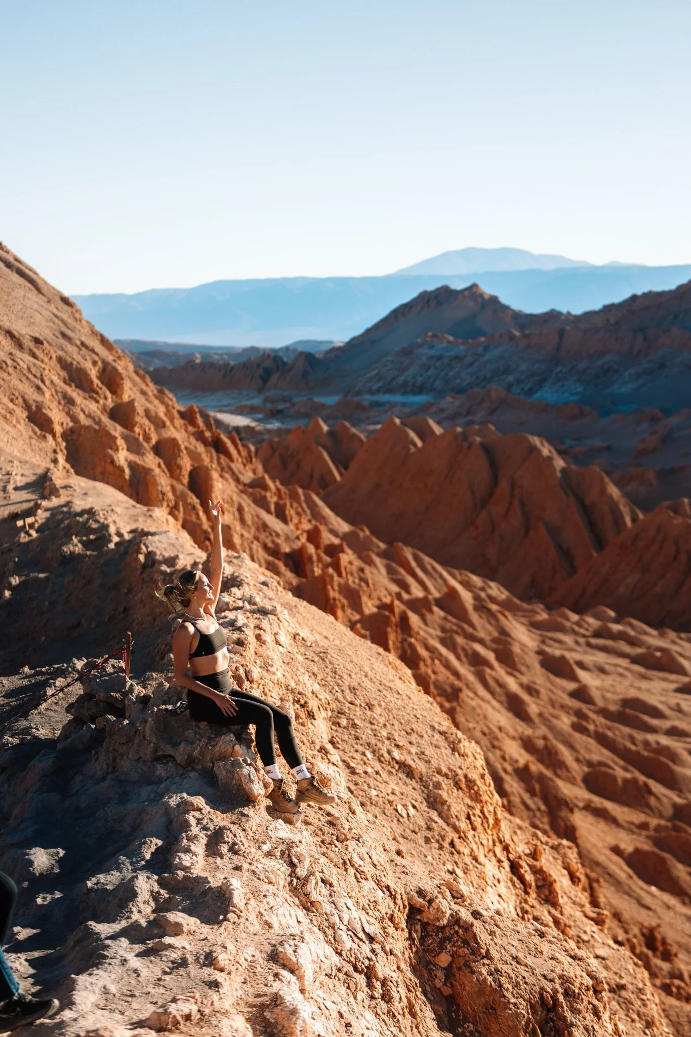 Standing on a ridge above the wind-carved red badlands of Valle de la Luna in the Atacama Desert at golden hour