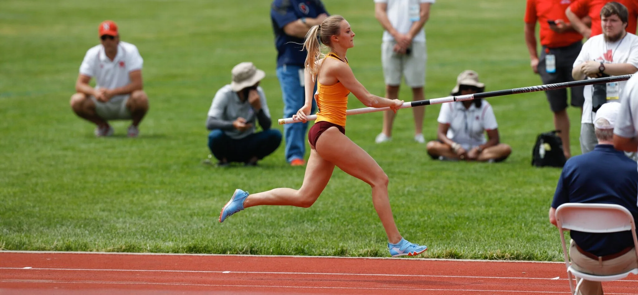 Karlie Place pole vaulting in college competition, soaring over the bar