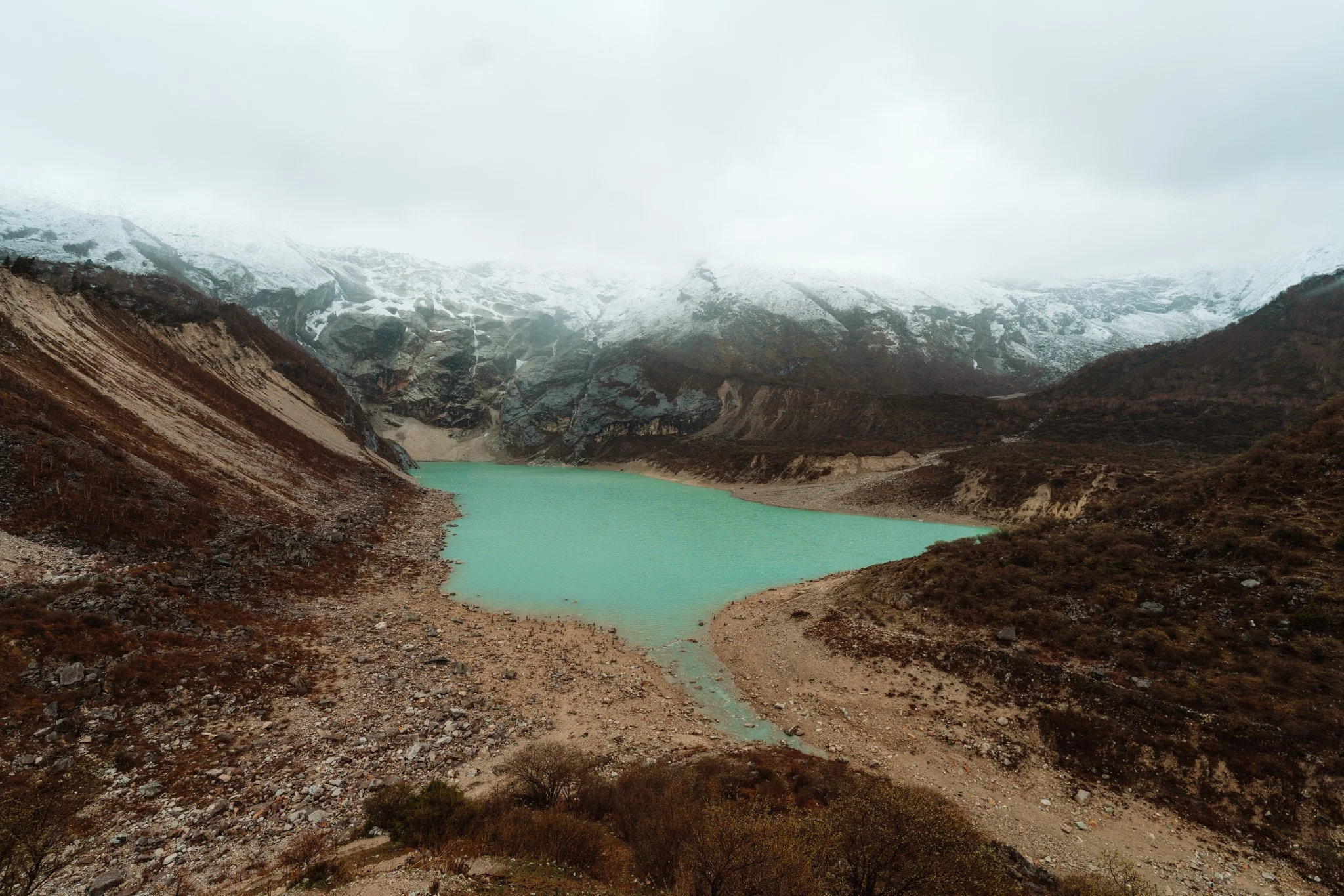 Bright turquoise Birendra glacial lake at the foot of Manaslu mountain on day six of the Manaslu Circuit Trek in Nepal