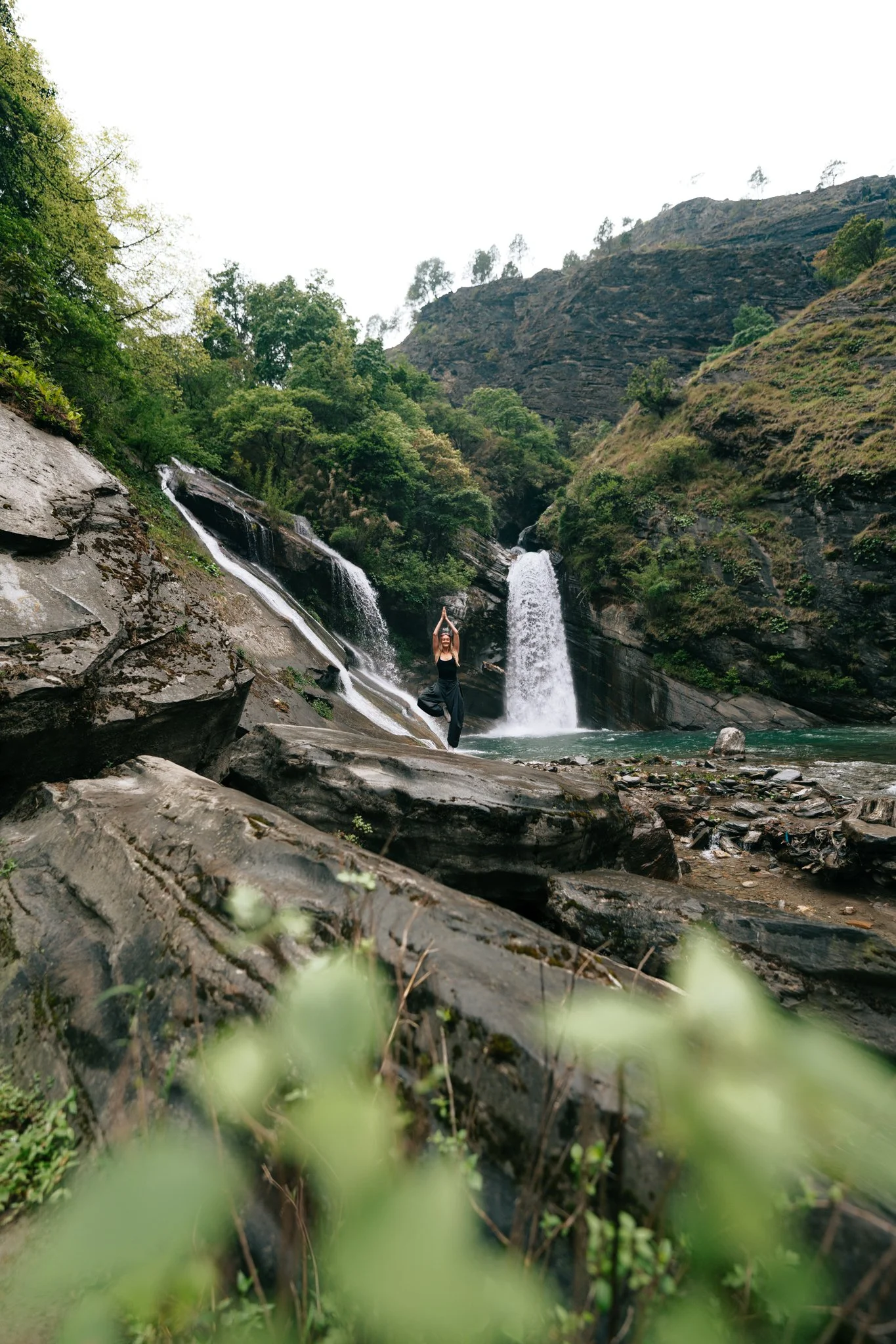 Solo female trekker beside dual cascading waterfalls just outside Jagat village on day two of the Manaslu Circuit Trek in Nepal
