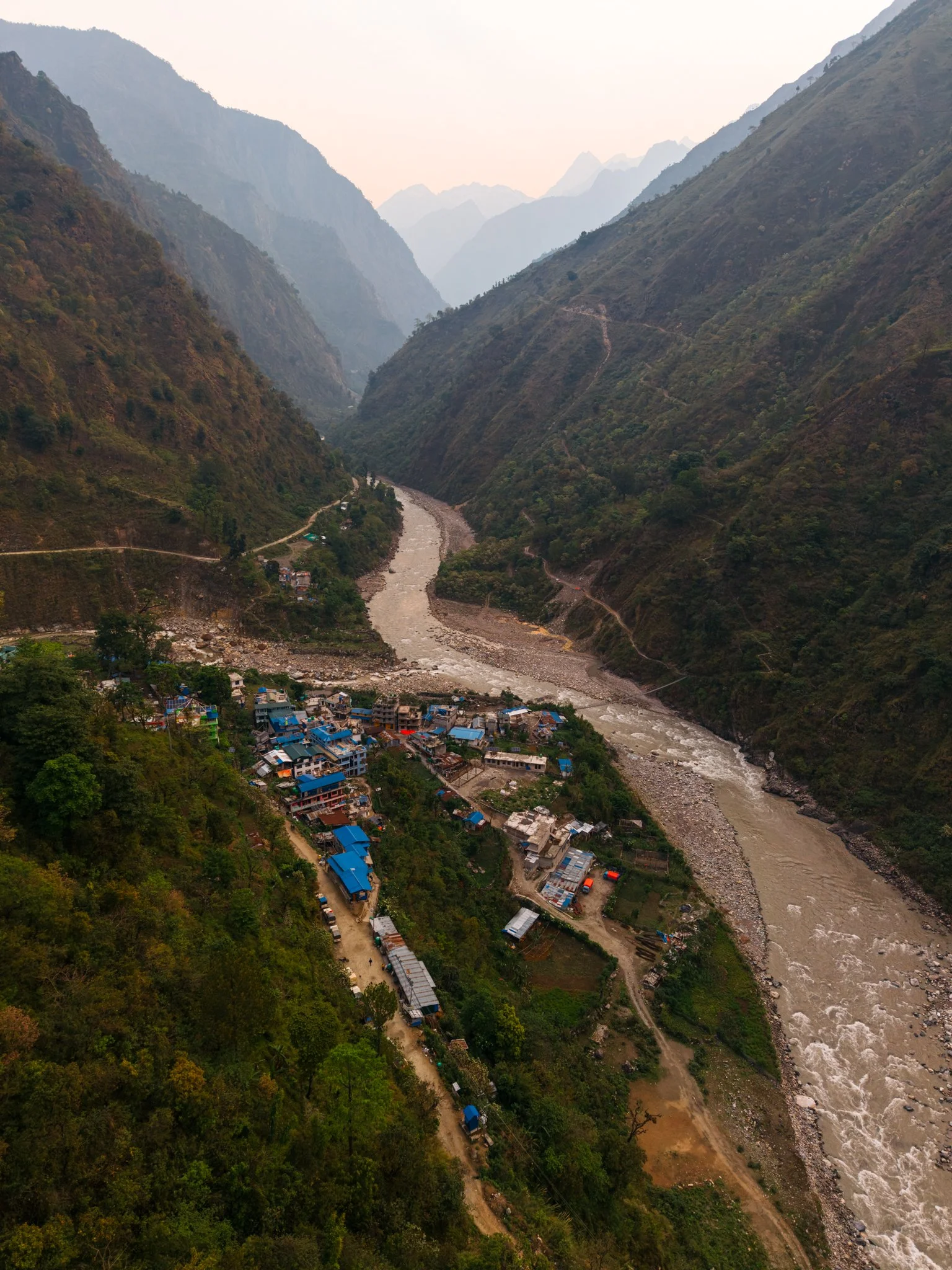 Aerial view of Machha Khola village with colorful corrugated roofs along the Budhi Gandaki river, the starting point of the Manaslu Circuit Trek