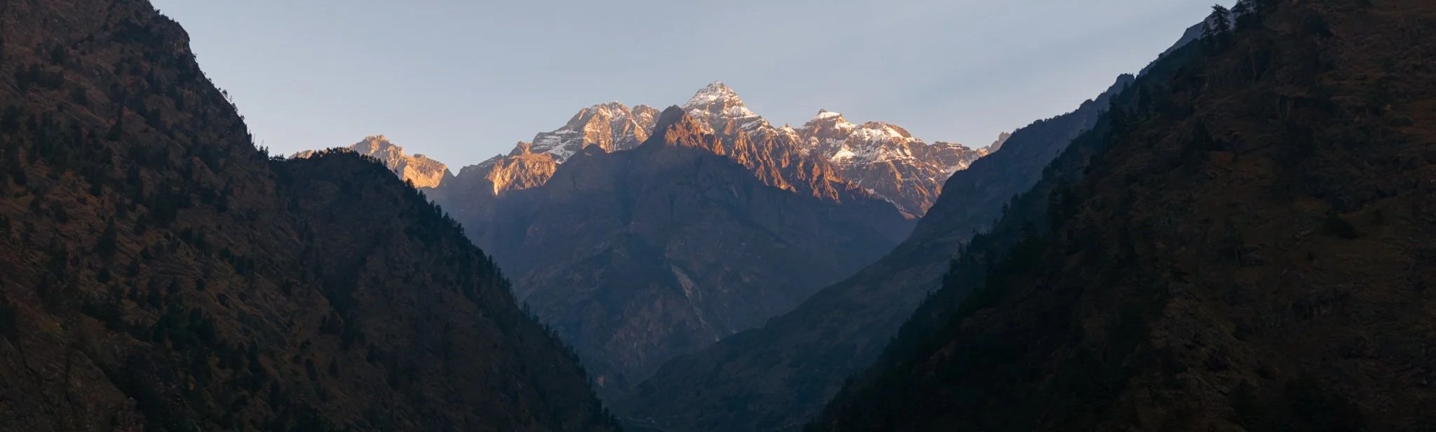 Sunset alpenglow on distant snow-covered Himalayan peaks visible from Jagat village on day one of the Manaslu Circuit Trek