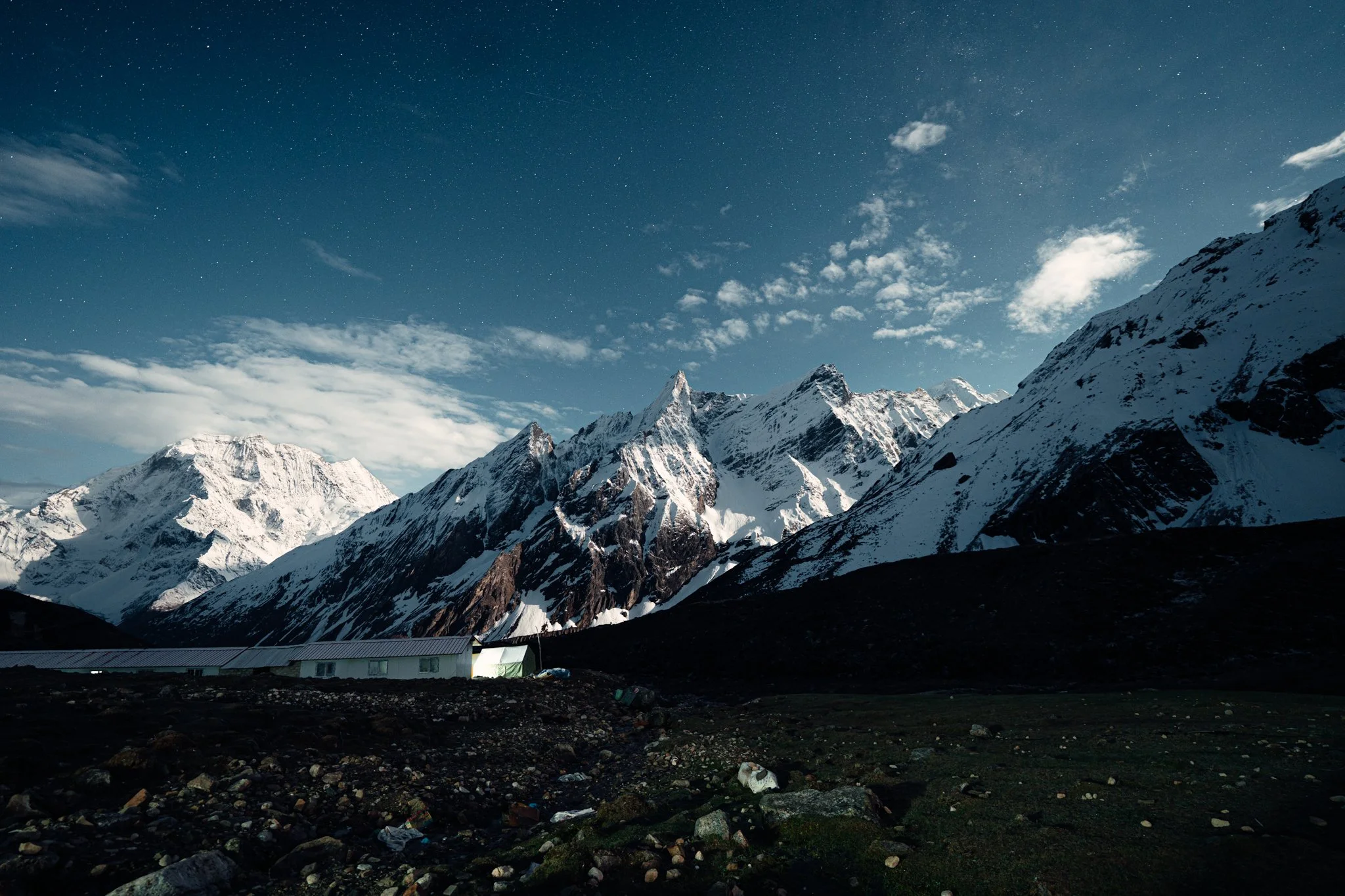 Long exposure nightscape of glowing teahouses under stars and moonlit Manaslu peak at Dharamsala high camp on the Manaslu Circuit Trek
