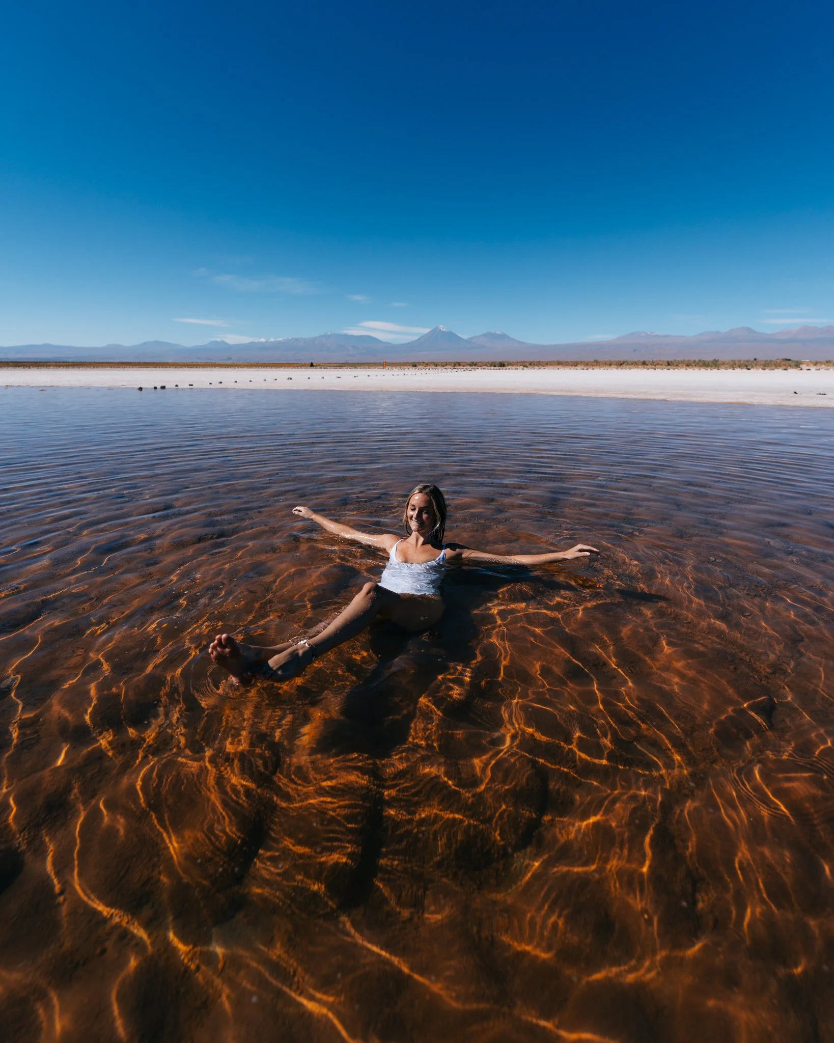 Floating effortlessly in the clear hypersaline water of Cejar Lagoon with Andean volcanoes on the horizon