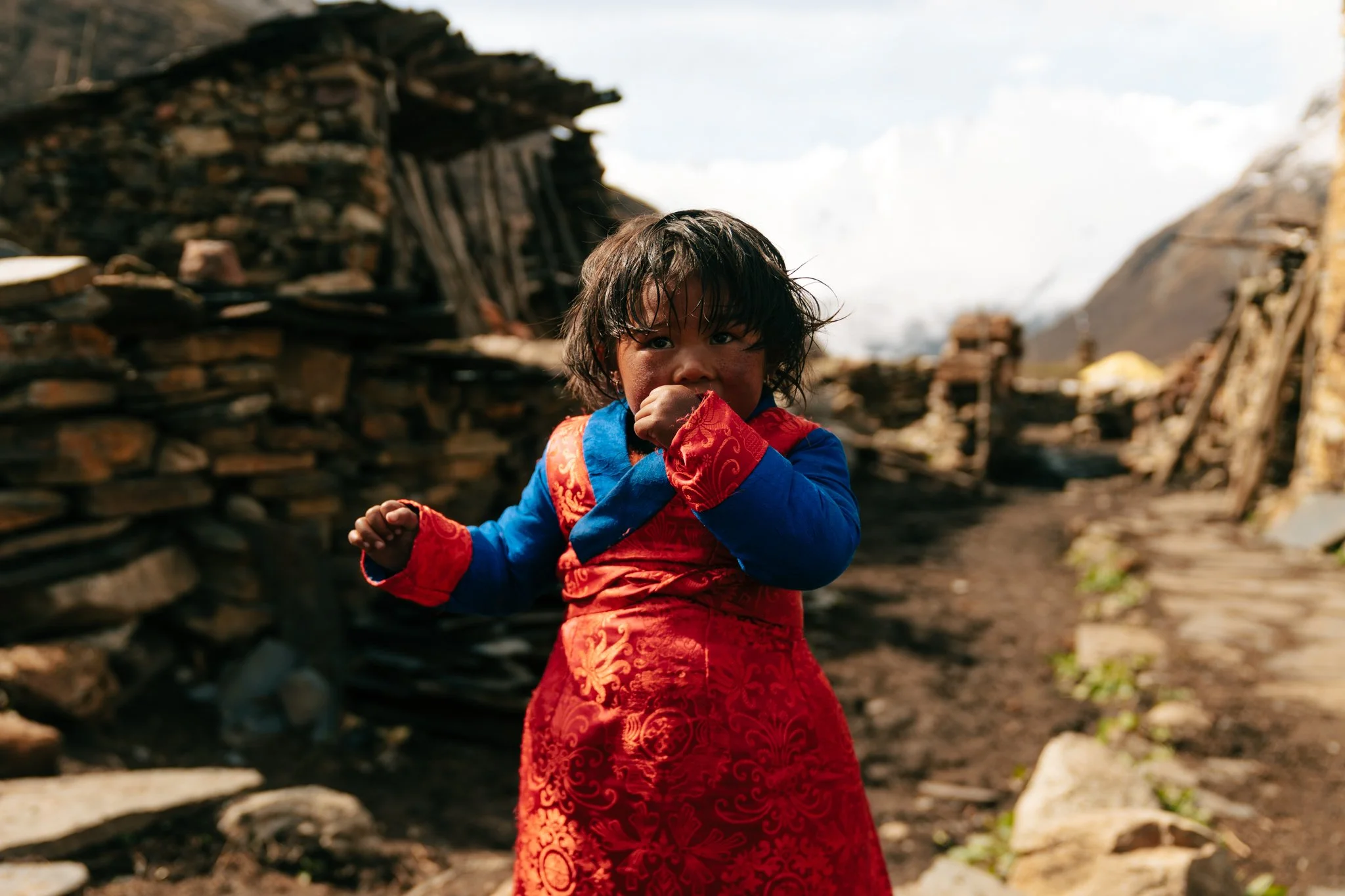 Young Tibetan girl wearing a traditional red and blue silk chuba ceremonial dress for Saga Dawa festival in Samdo village on the Manaslu Circuit Trek