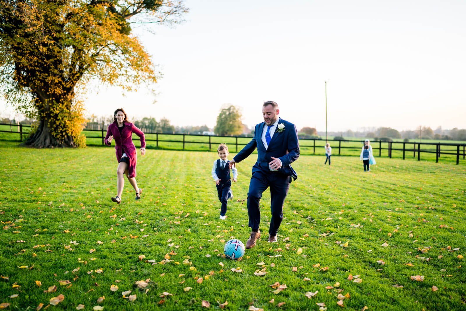 groom plays football with guests at barford park