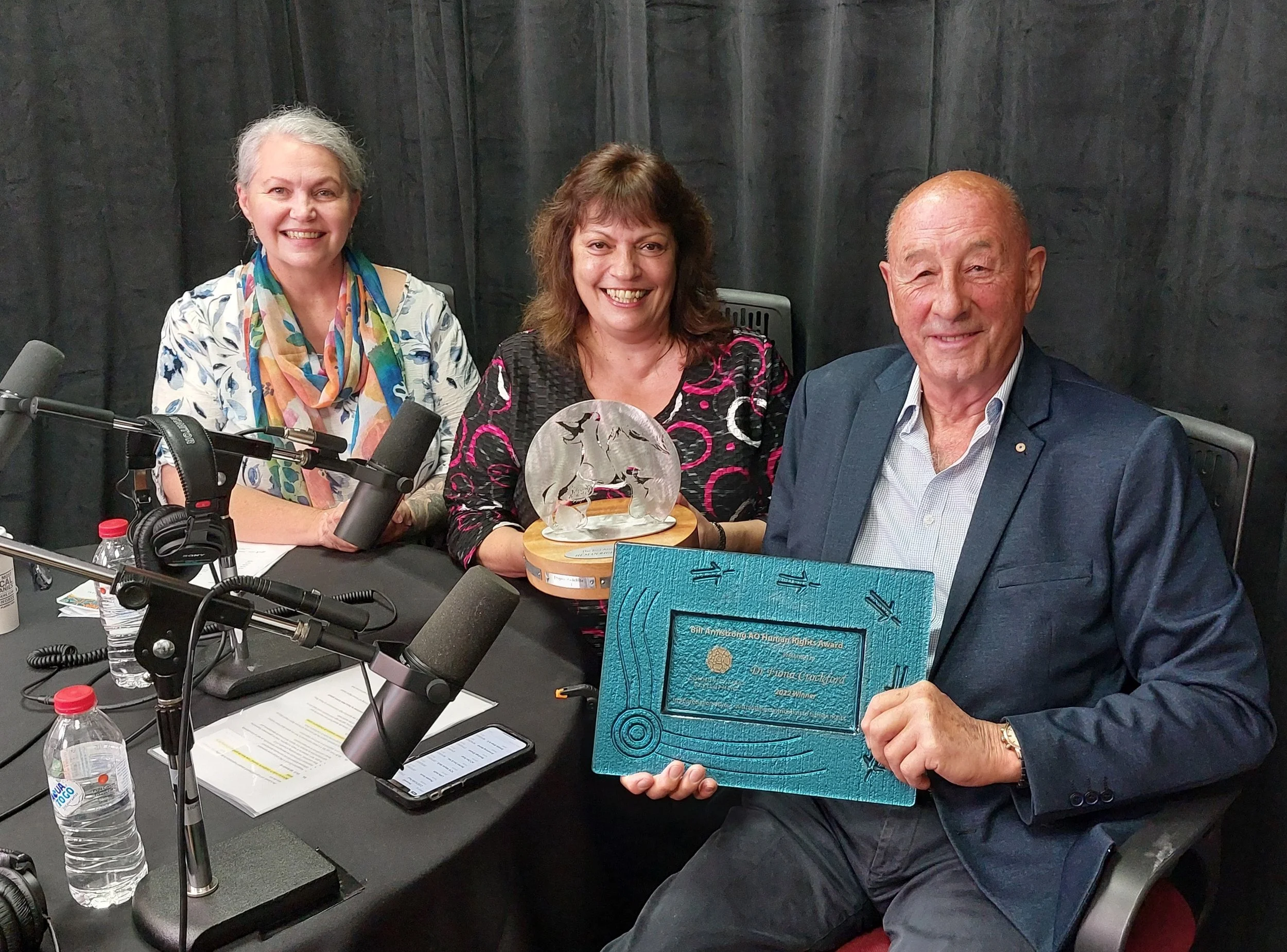  The Award was presented from a studio in Australia, to Dr Crockford who attended the event via video link from the Australian High Commission in Port Moresby, Papua New Guinea alongside HE Jon Philp – Australian High Commissioner to Papua New Guinea.  Image: from left, Stephanie Harvey CEO Community First Development, Karen Milward Chair Community First Development, Bill Armstrong AO. 
