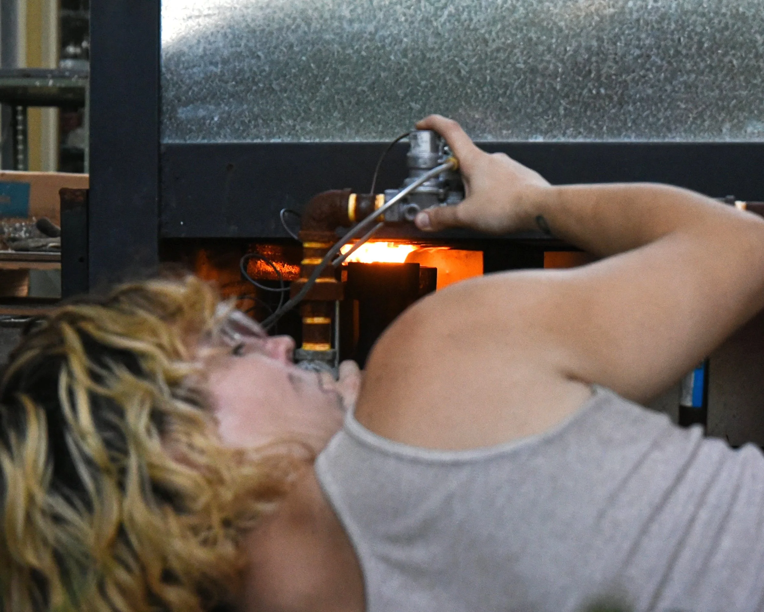  Dakota Parkinson, ceramic artist and teacher, adjusts the gas valves underneath the kiln Sept. 21, 2021. The kiln requires continuous observation and management.  