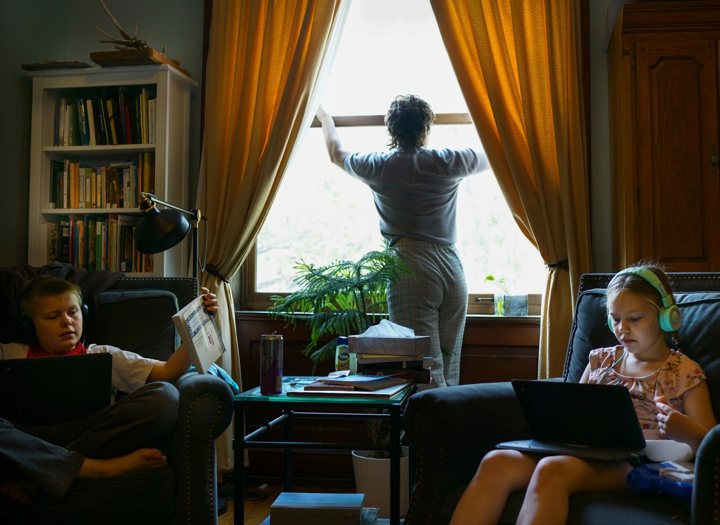  Abi opens the window to let in the spring breeze April 26, 2021 in St. Louis, Missouri. Abi nannies for Everett, 10, left, and Brandeis, 8, right, while the siblings attend remote classes during the COVID-19 pandemic.  