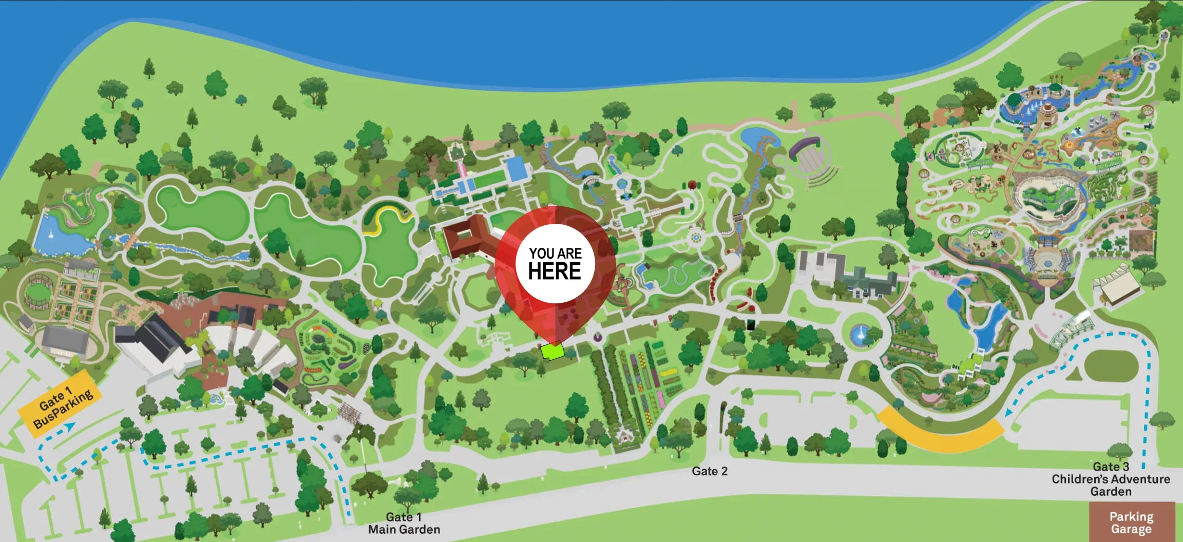 Colorful map of a large theme park with various attractions, water rides, gardens, and green spaces. A red marker indicates current location labeled 'You Are Here,' near the main entrance and parking areas.