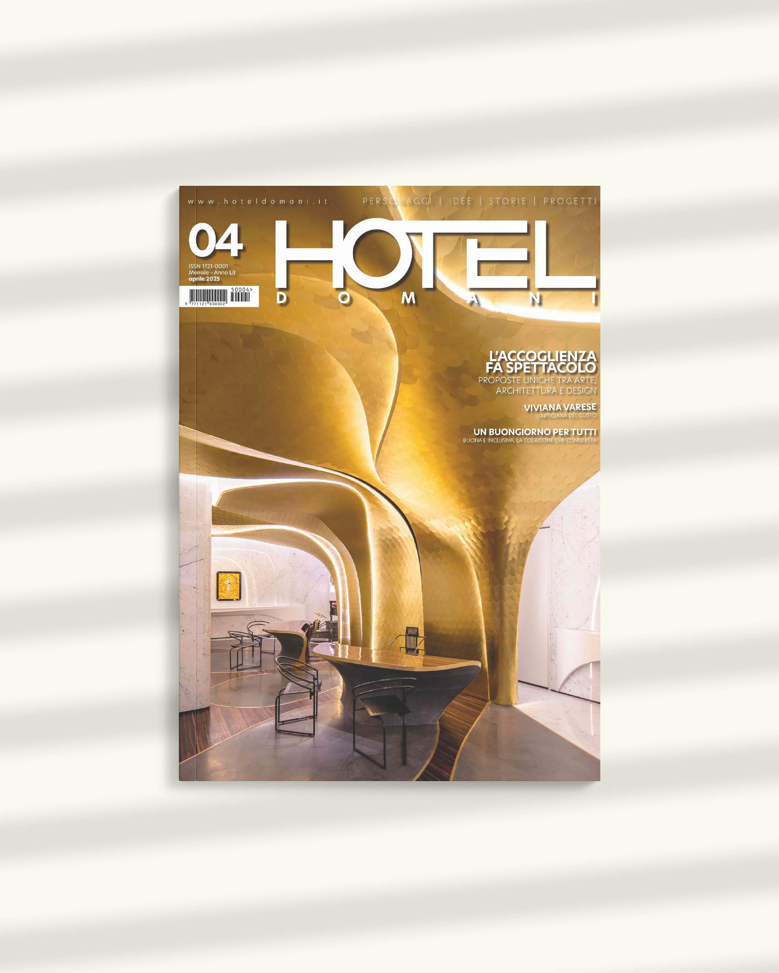Copertina di una rivista intitolata 'Hotel Domani', con un'immagine di un'atrio di hotel con pareti e soffitti in un colore oro brillante e mobili moderni.
