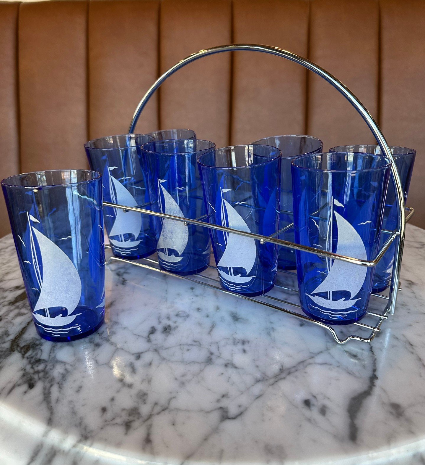 Vintage Find Alert! ⛵ Cobalt blue tumblers featuring classic sailboat graphics, complete with the original carrying caddy. Perfect for summer entertaining, lake house gatherings, or adding a nautical touch to your bar cart.