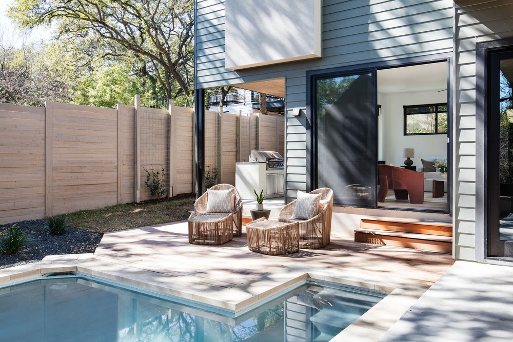 Outdoor pool area with grill area behind, sliding glass doors to living space