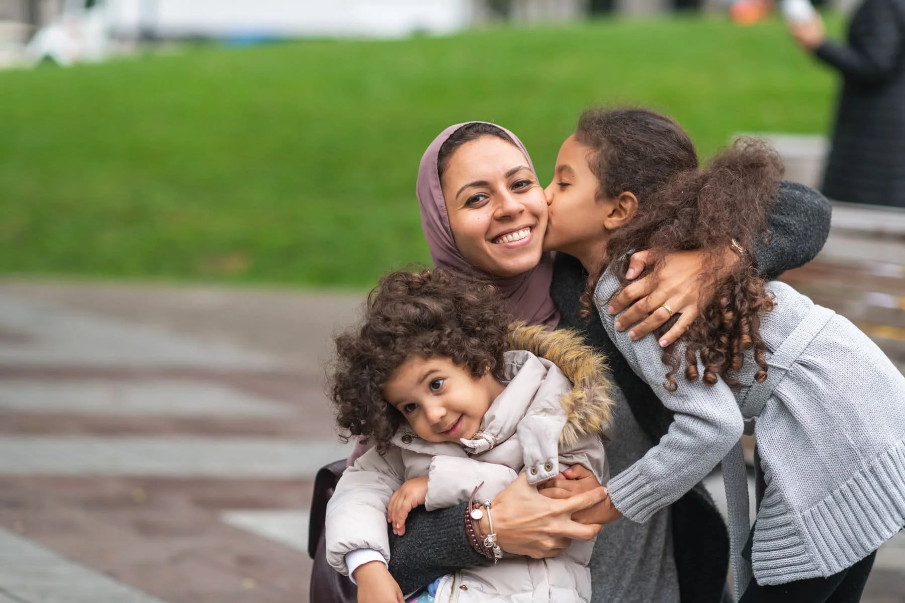 Muslim-mother-hugging-daughters-in-city-park-1175539119_2125x1416.jpeg