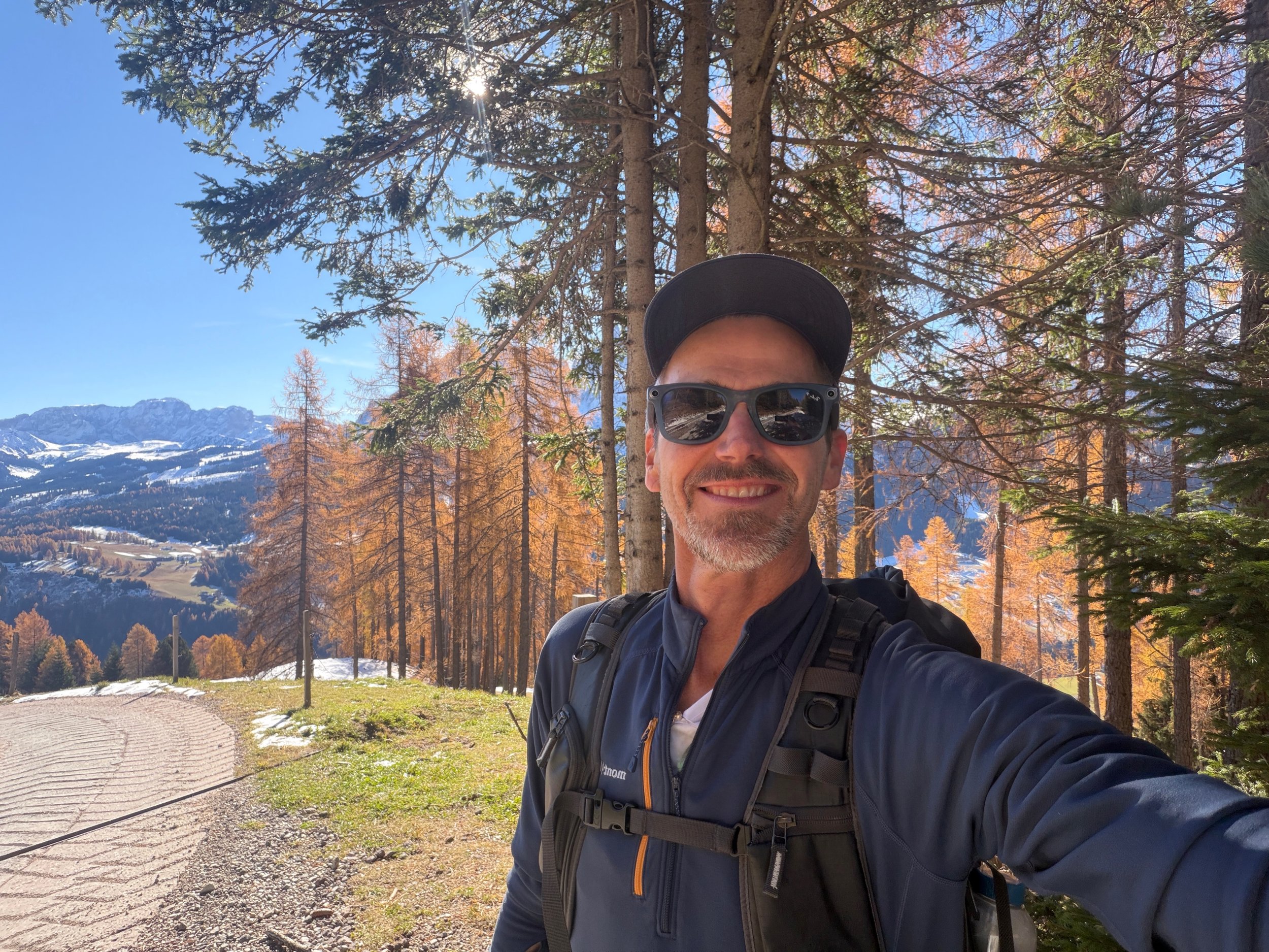 Landscape photographer Timothy Poulton hiking in the Dolomites during late autumn, surrounded by golden larch trees and early winter snow.