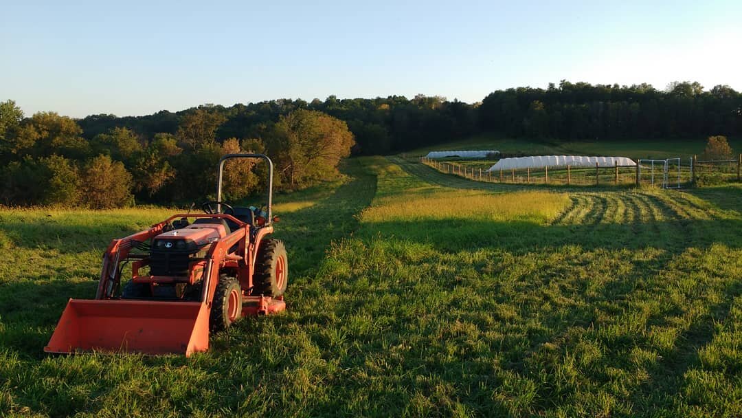 Farm field at sunset with orange tractor