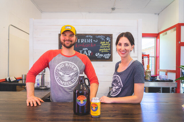 Two people serving kombucha from behind counter