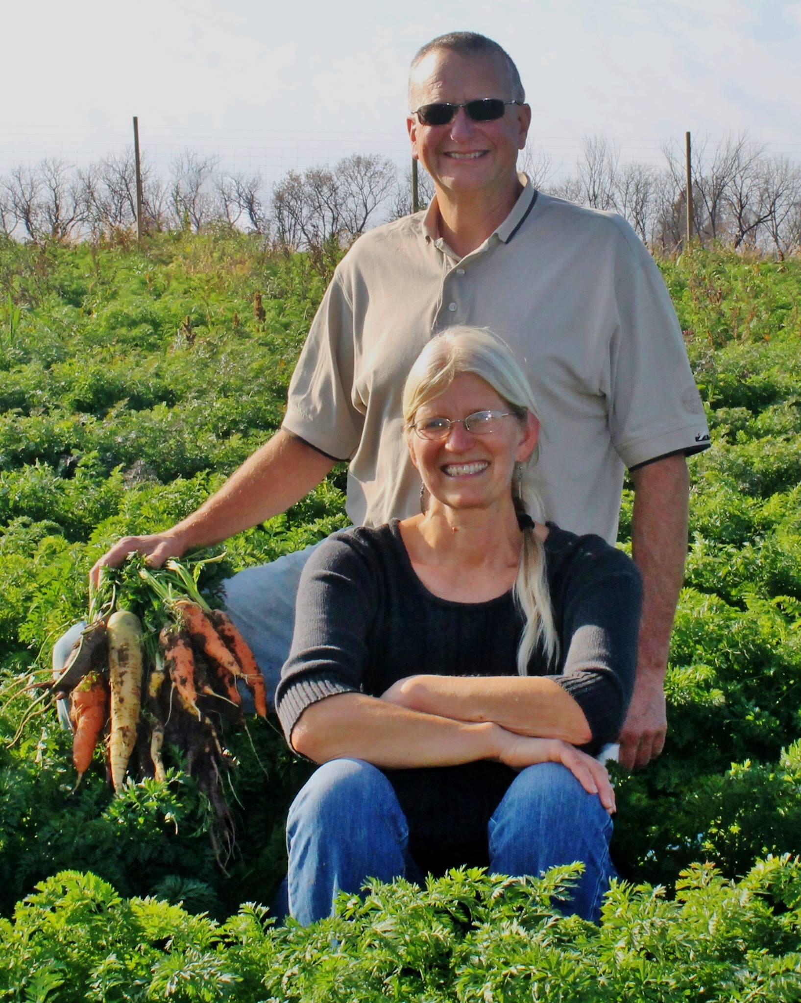 Whitewater Gardens Farm owners sitting in a green field